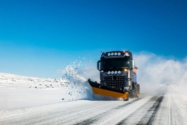 A truck is plowing snow on a snowy road.