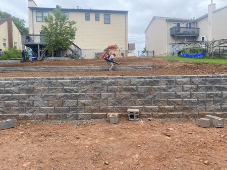 A man installing a stone retaining wall.