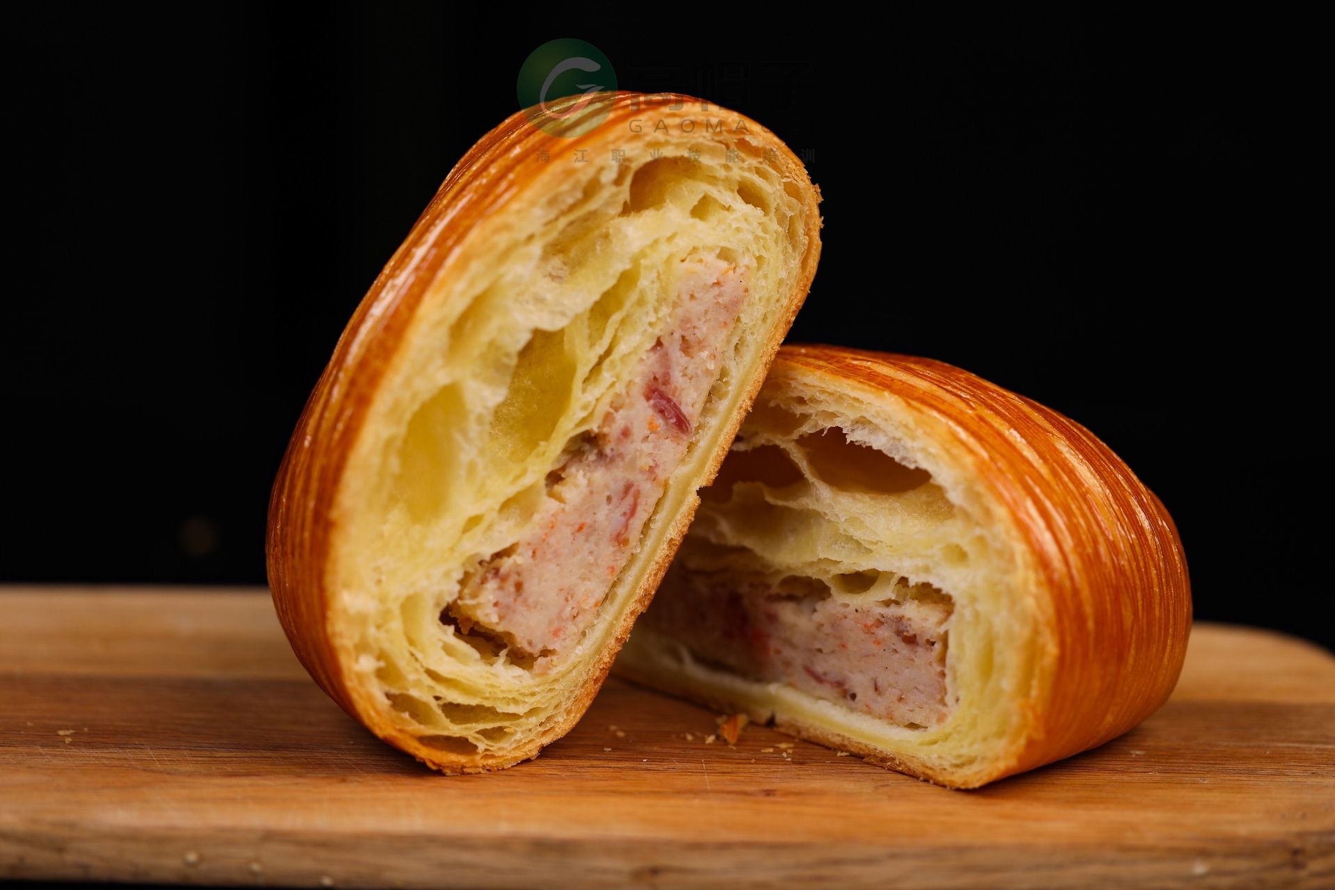 Deux croissants sont coupés en deux sur une planche à découper en bois.