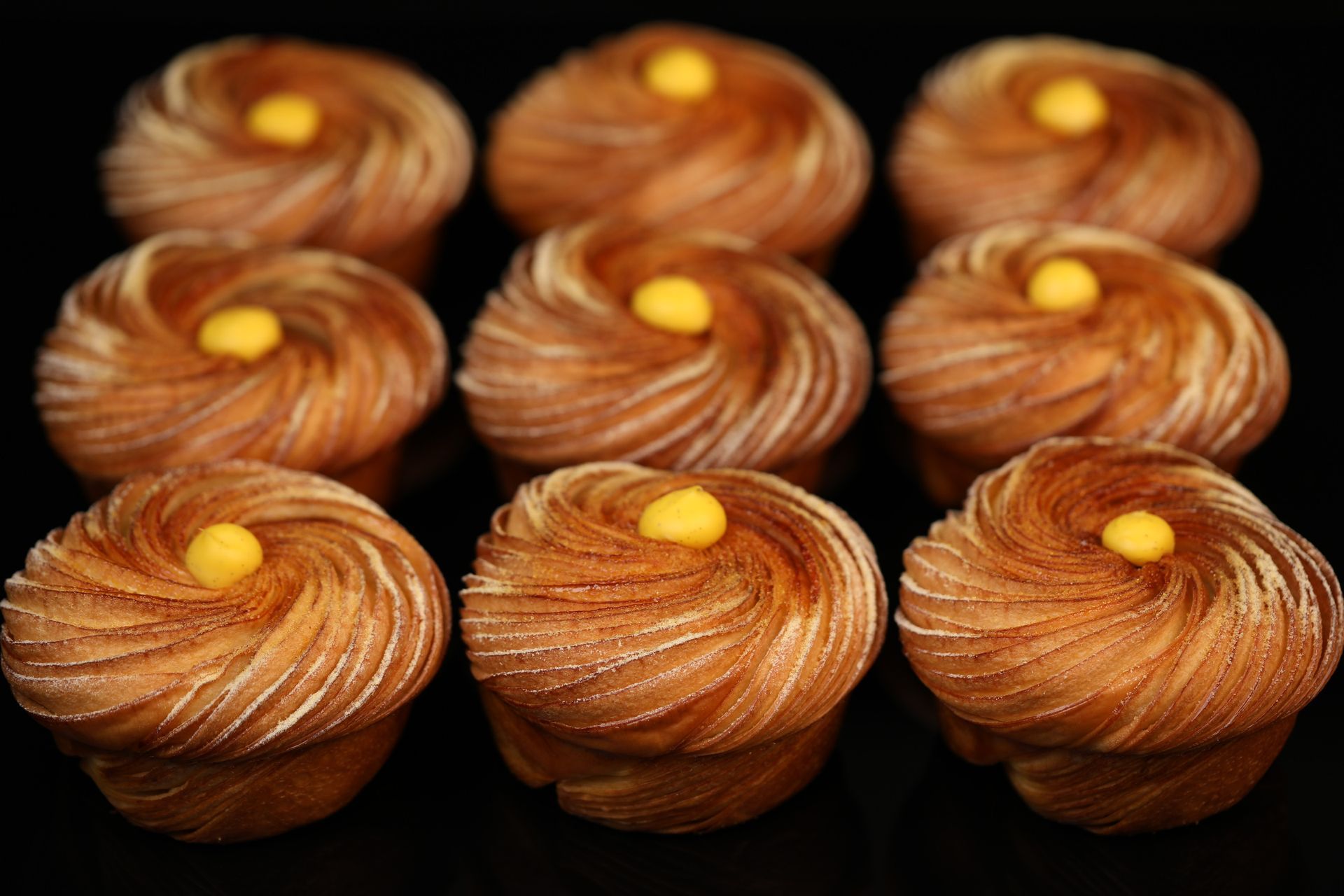 Un tas de cupcakes avec un glaçage jaune sur fond noir