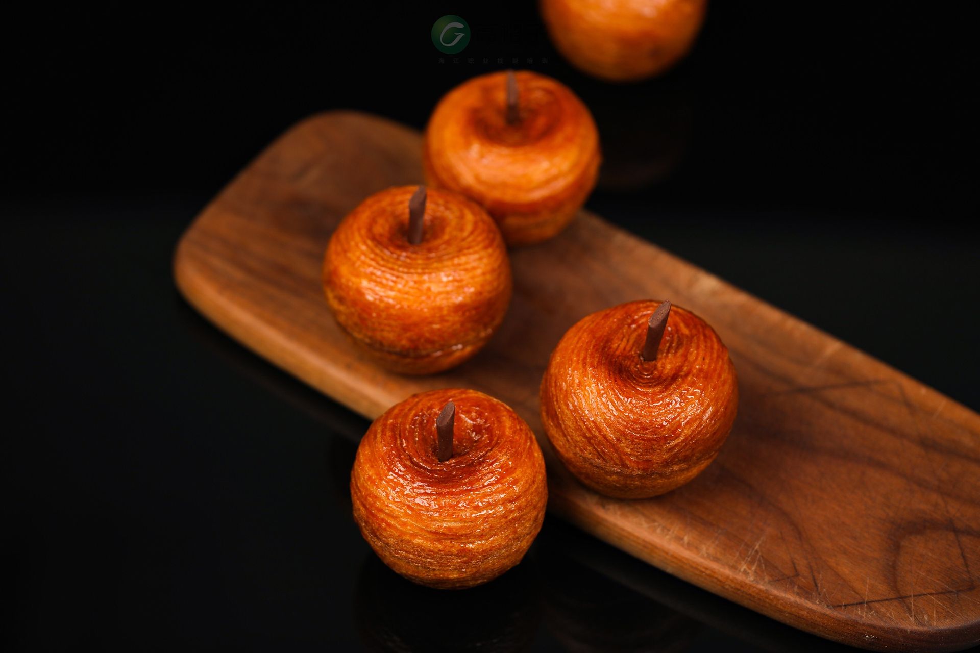 Quatre beignets en forme de pommes sont posés sur une planche à découper en bois.