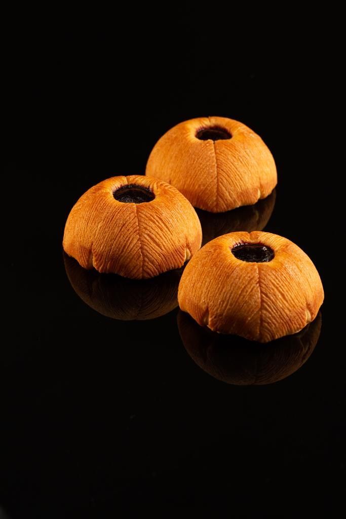 Trois morceaux de pain avec un trou au milieu sur une surface noire.