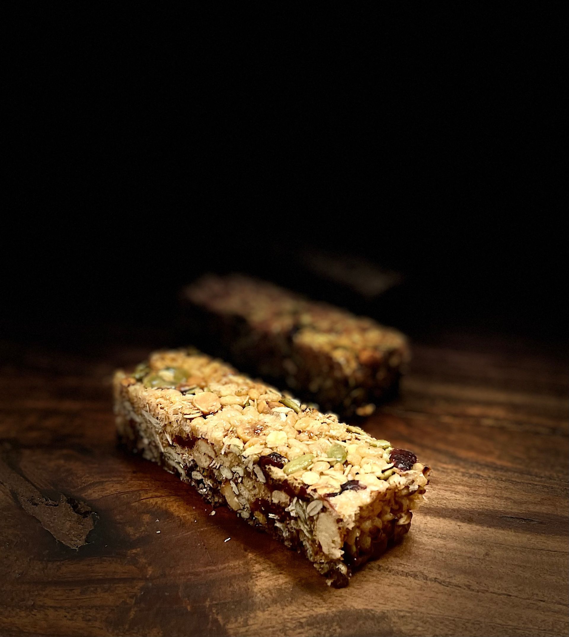 Deux barres de céréales sont posées sur une table en bois.
