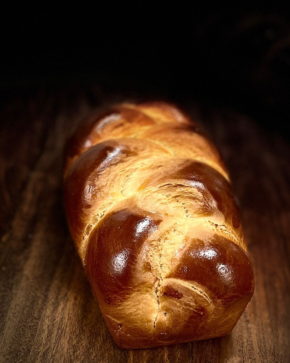 Une miche de pain challah est posée sur une table en bois.