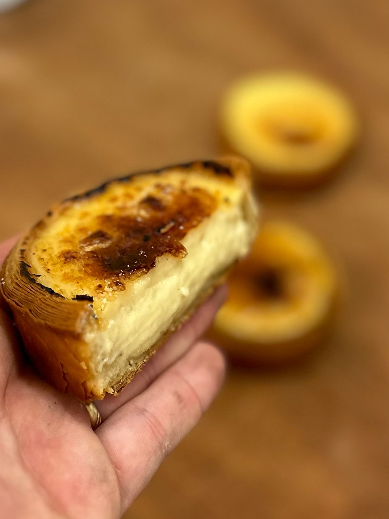 Une personne tient un morceau de cheesecake dans sa main.