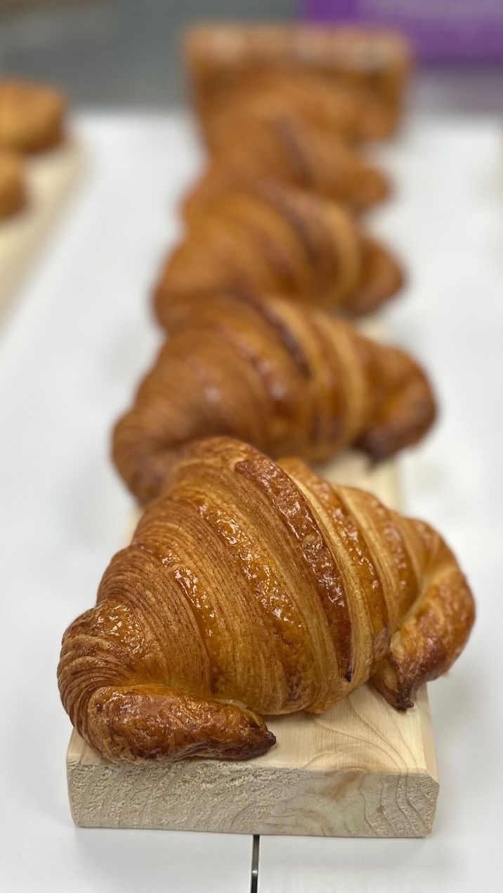 Une rangée de croissants posée sur une planche à découper en bois.