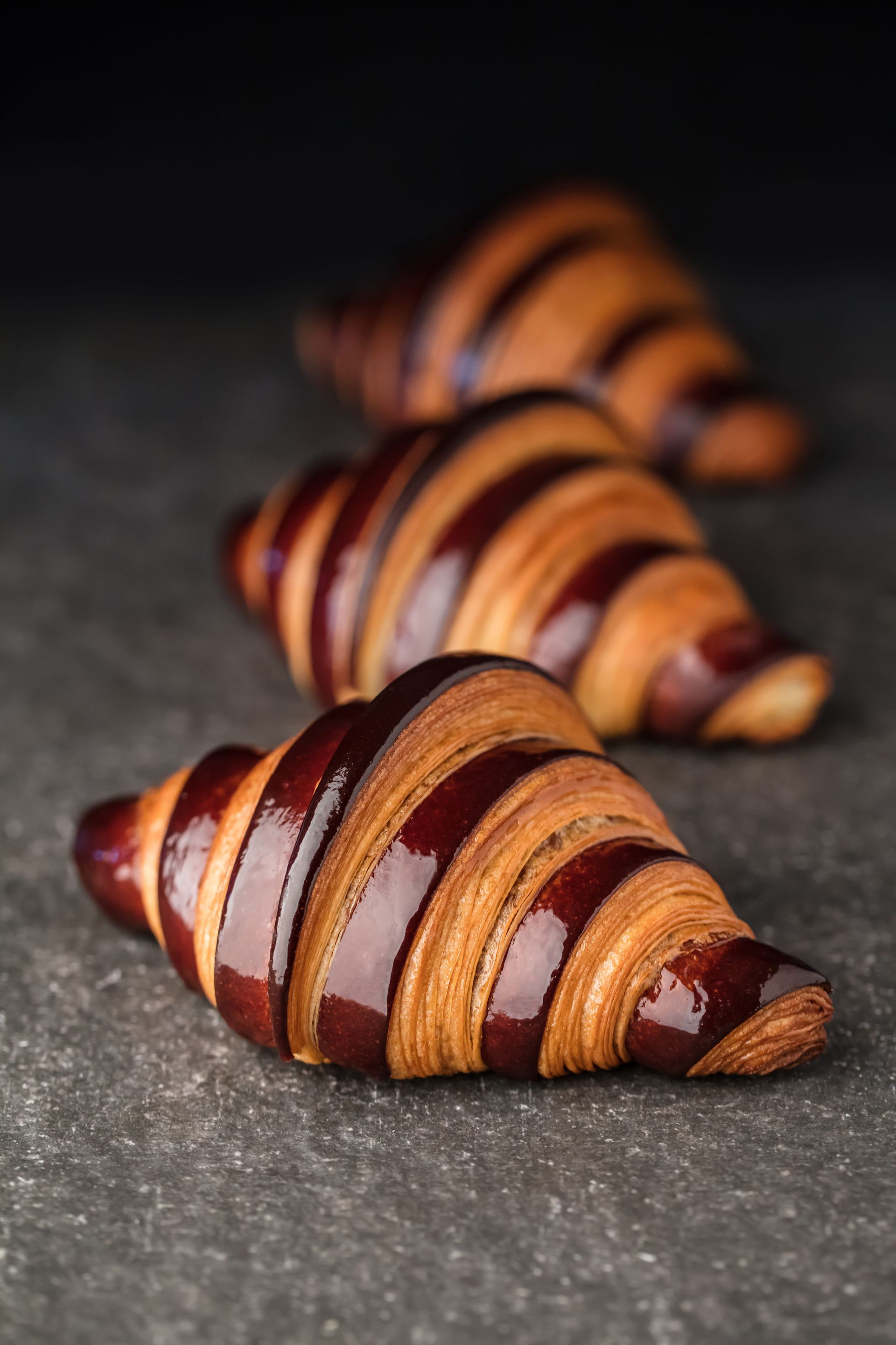 Trois croissants au chocolat sont alignés sur une table.