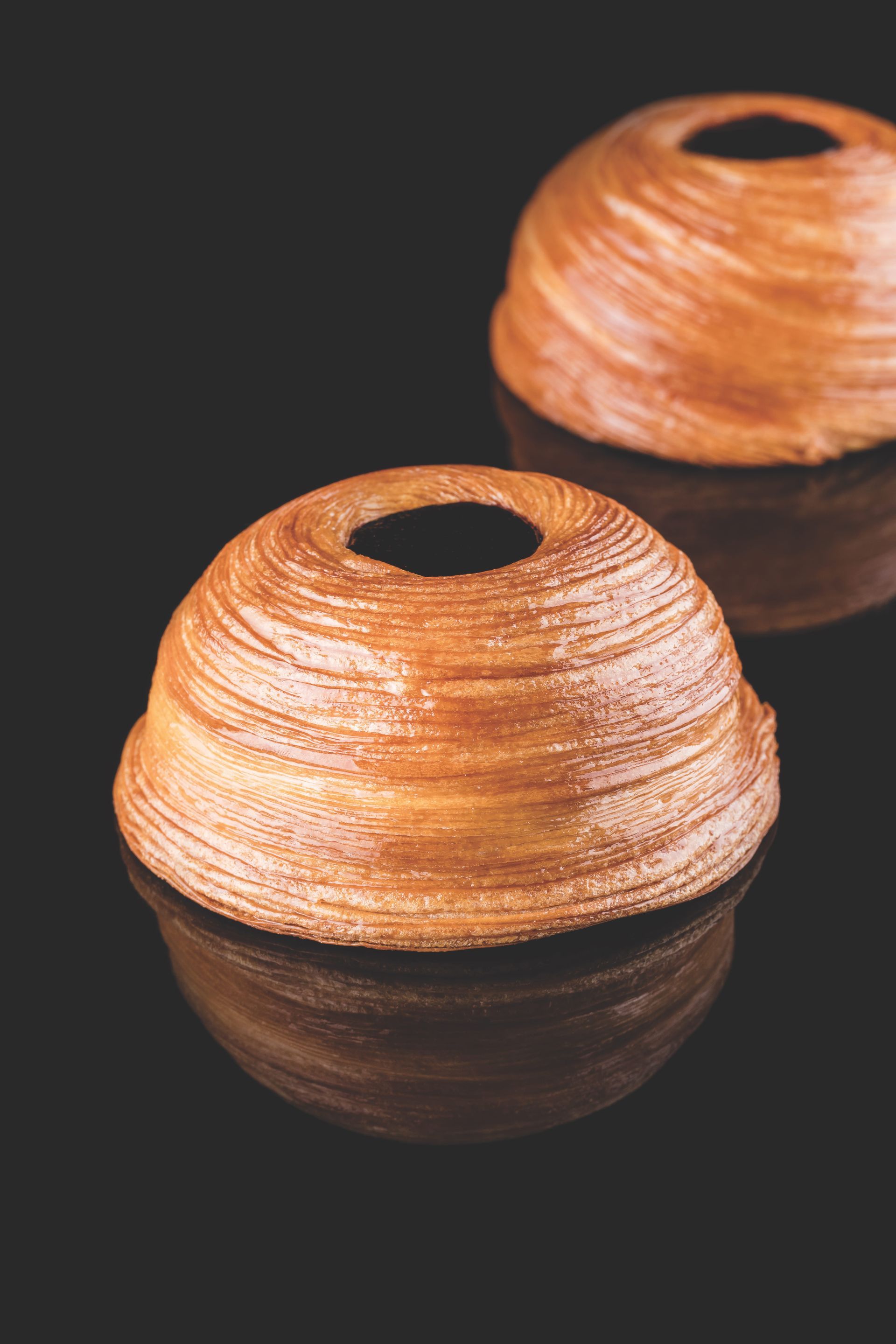 Deux morceaux de pain avec un trou au milieu sur une surface noire.