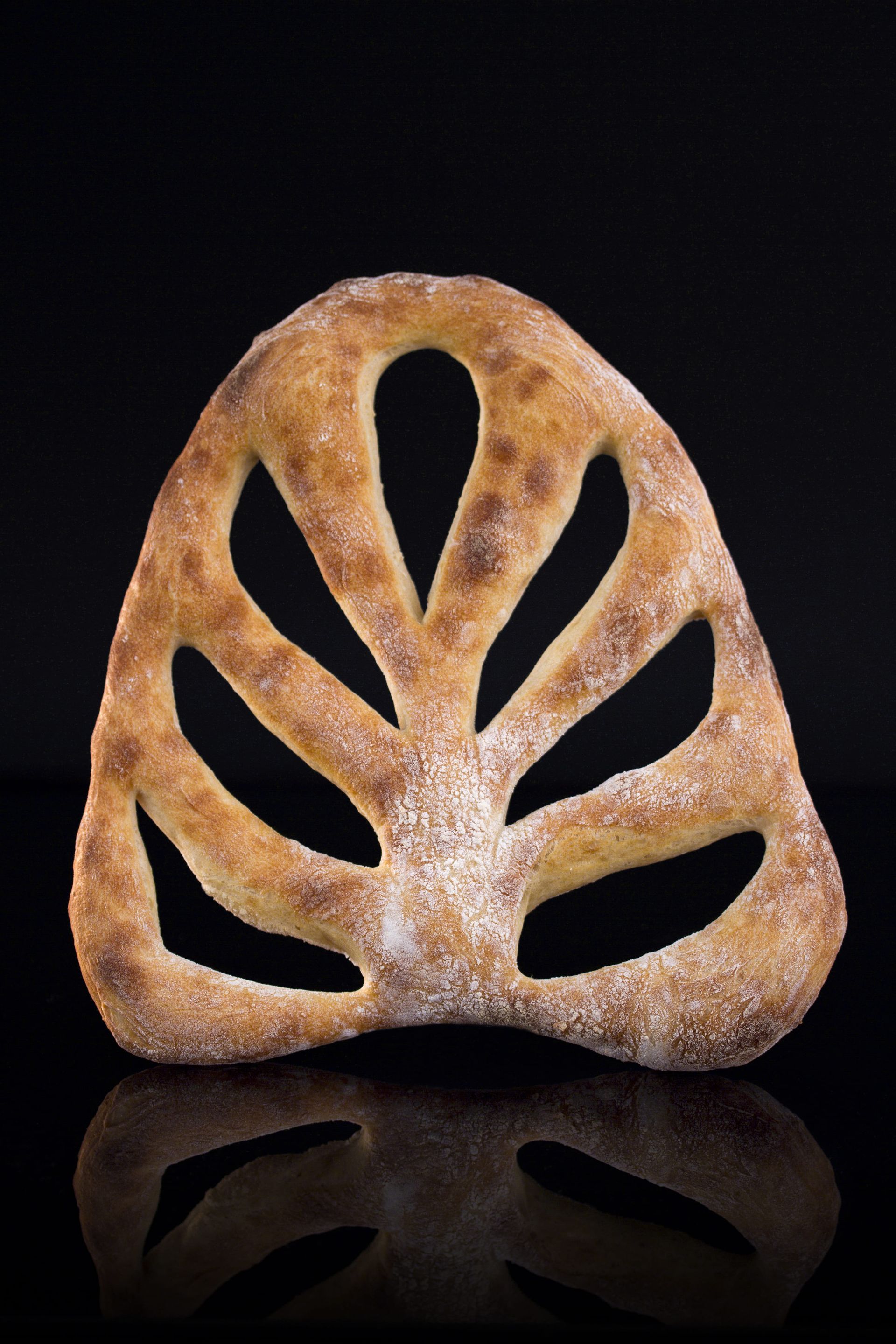 Un morceau de pain qui ressemble à une feuille est sur une surface noire.