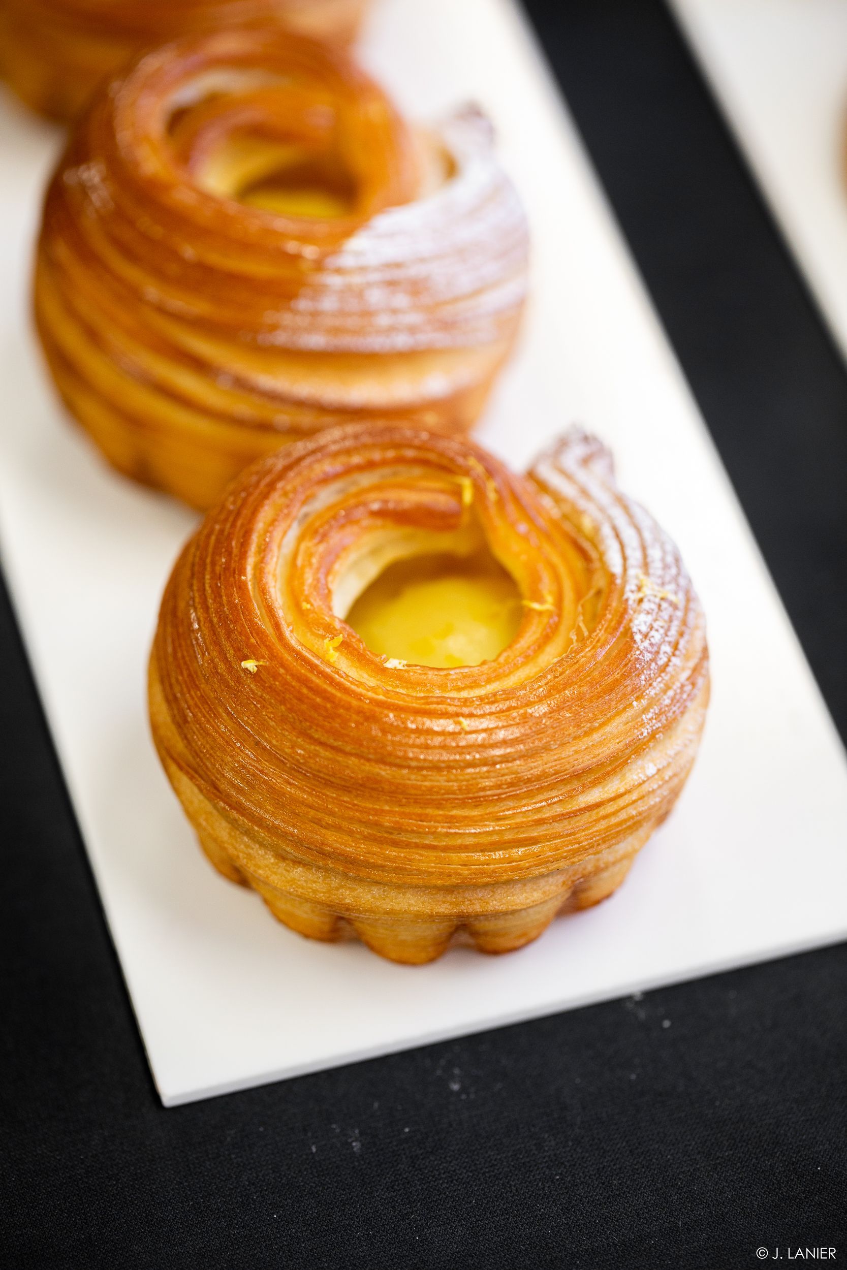 Un gros plan de trois pâtisseries sur une assiette blanche sur une table.