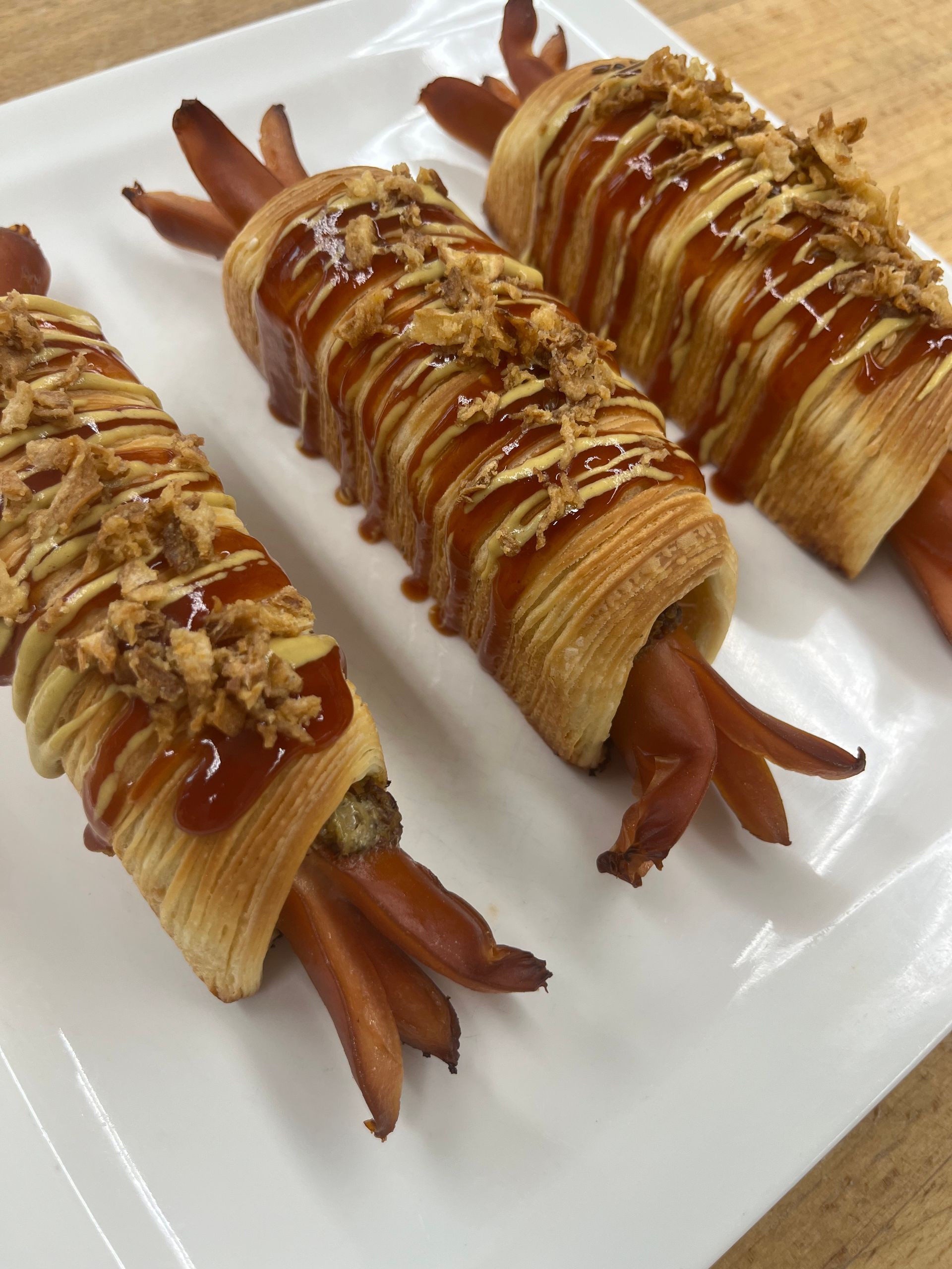 Deux hot-dogs enveloppés dans de la pâte feuilletée sur une assiette blanche