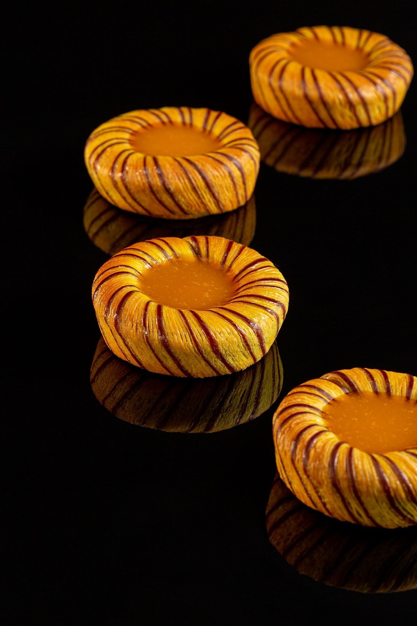 Un gros plan de quatre beignets sur une surface noire.