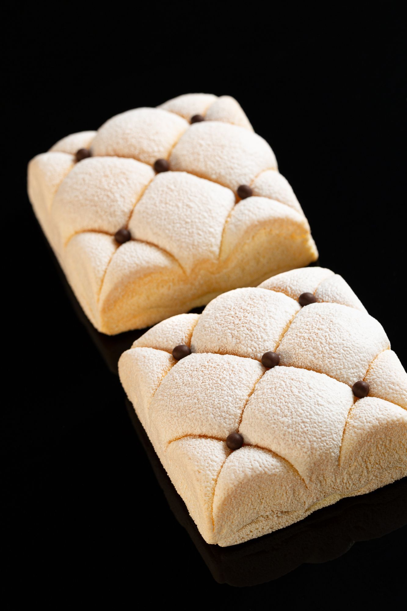 Un gros plan de deux morceaux de pain sur une surface noire.