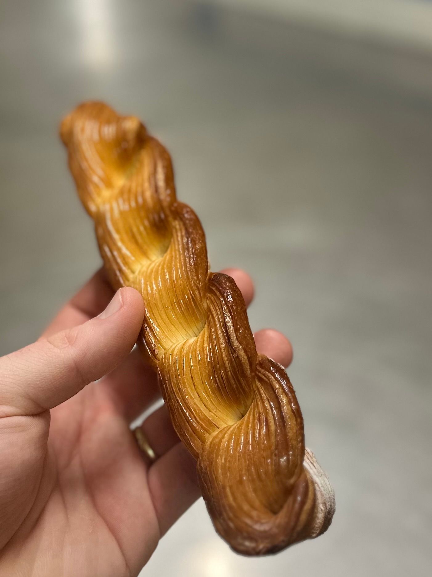 Une personne tient une pâtisserie torsadée dans sa main