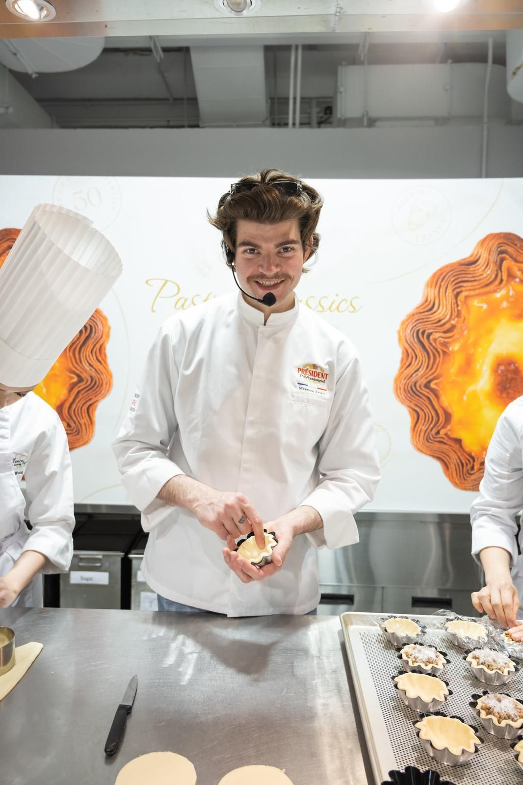 Un homme en uniforme de chef tient une pâtisserie dans ses mains.