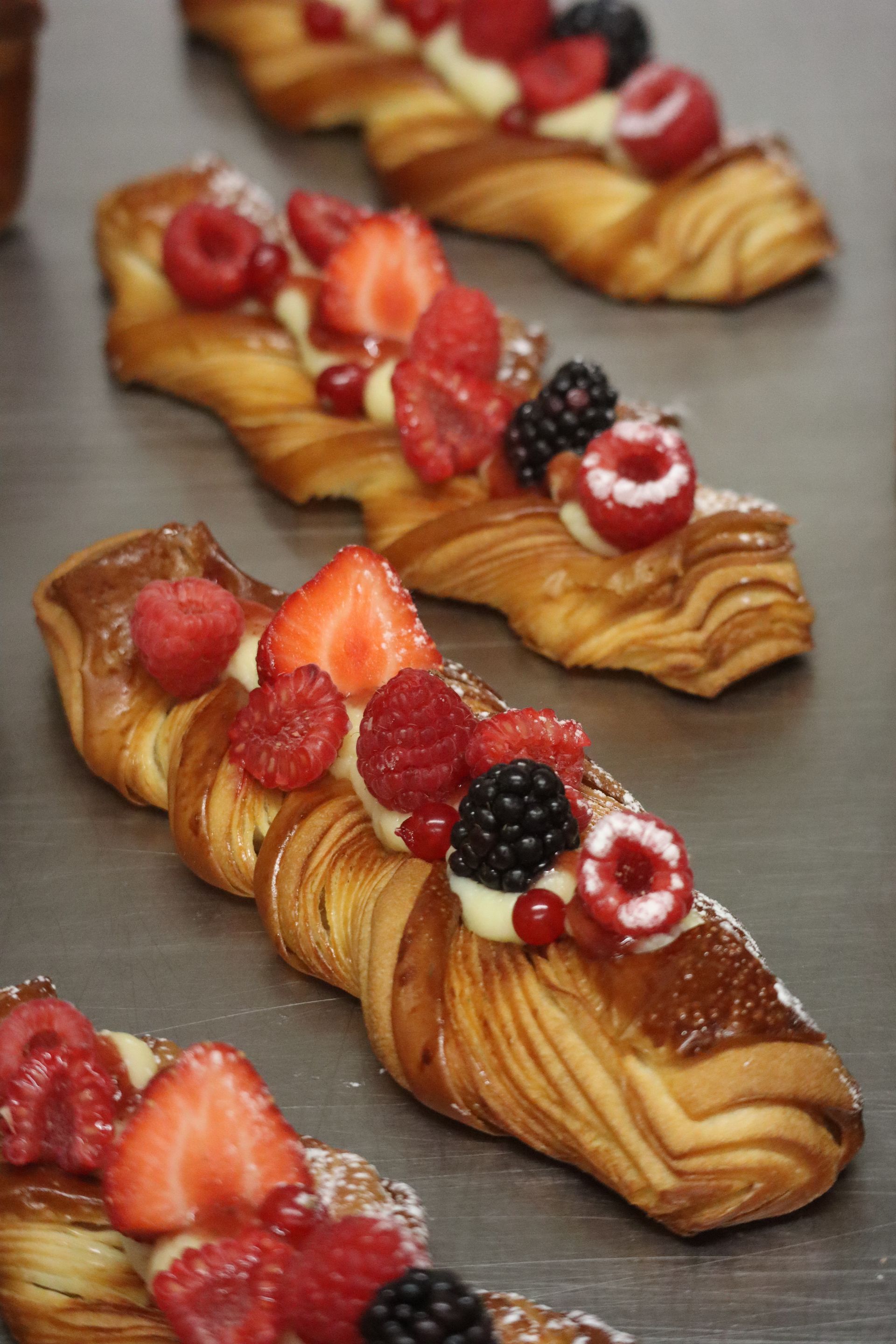 Une rangée de pâtisseries avec des baies dessus est posée sur une table.