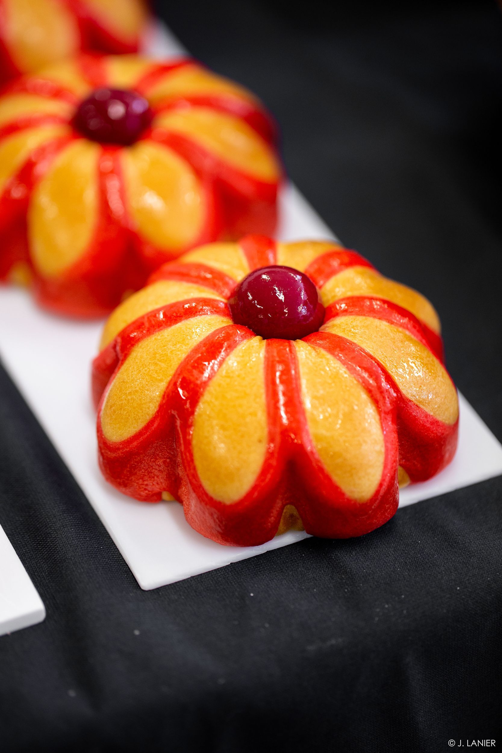 Un gros plan d'un dessert en forme de fleur avec une cerise sur le dessus.