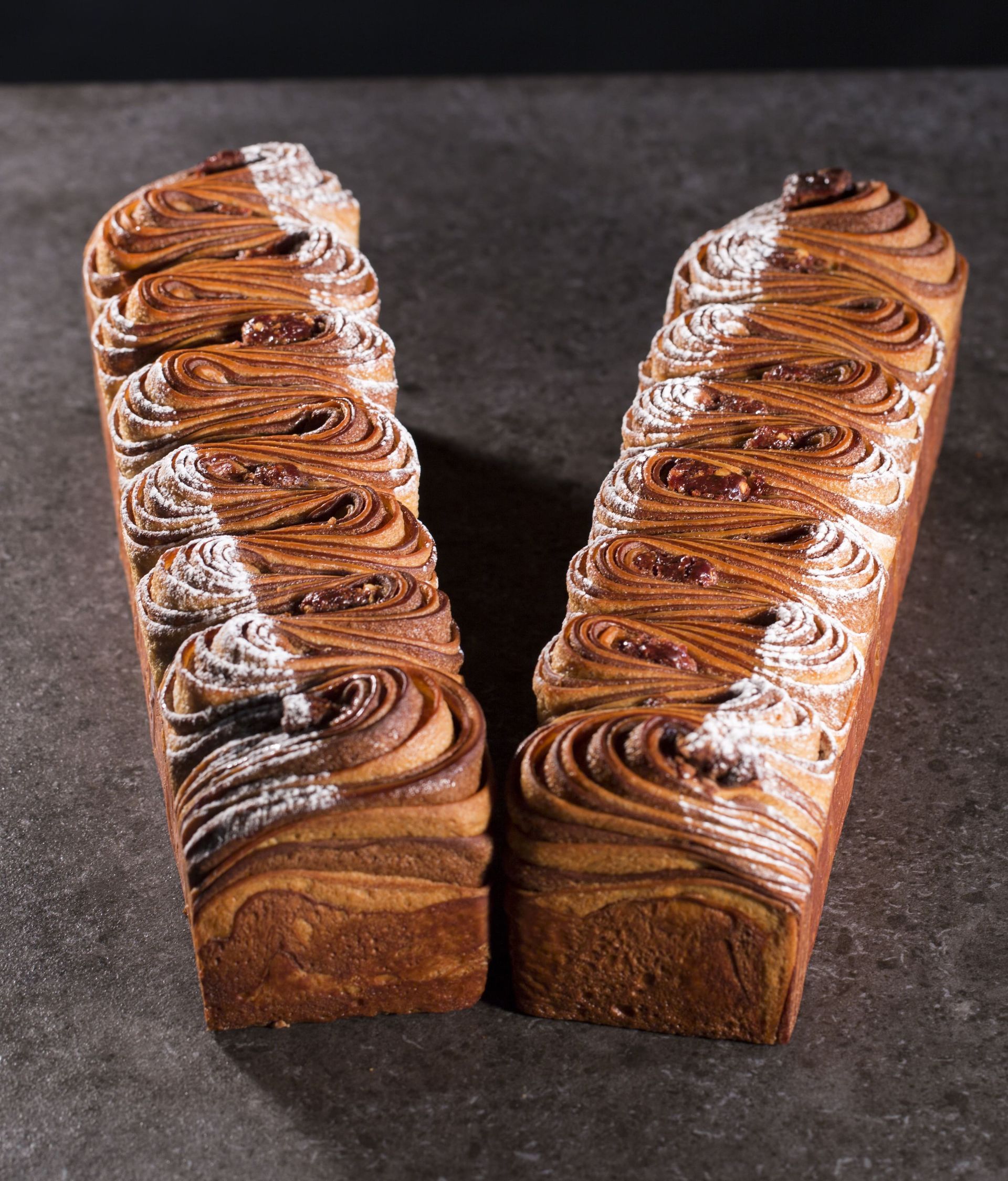 Deux morceaux de pain au chocolat sont posés l'un à côté de l'autre sur une table.