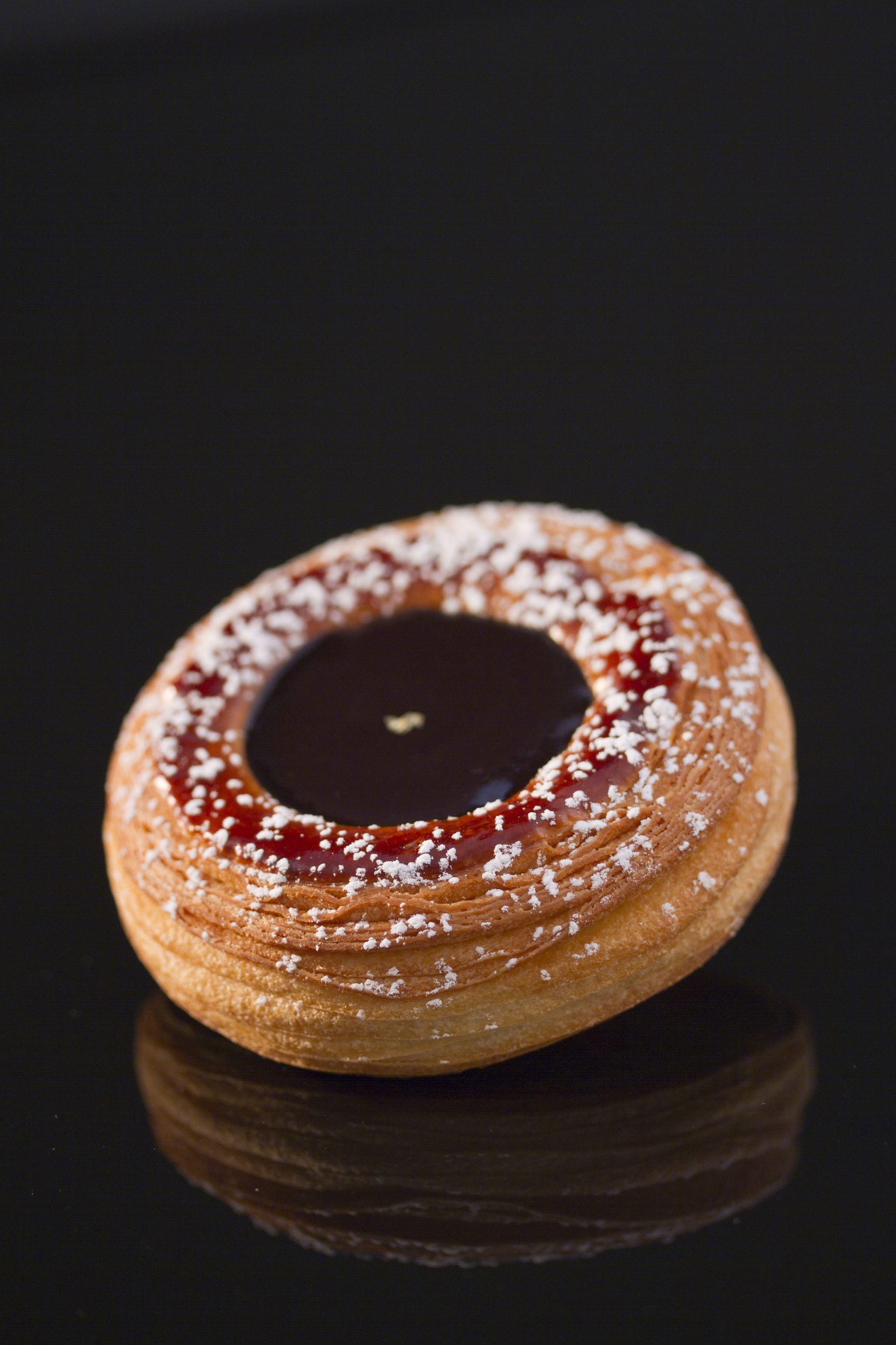 Un gros plan d'une pâtisserie avec du sucre en poudre sur une surface noire.