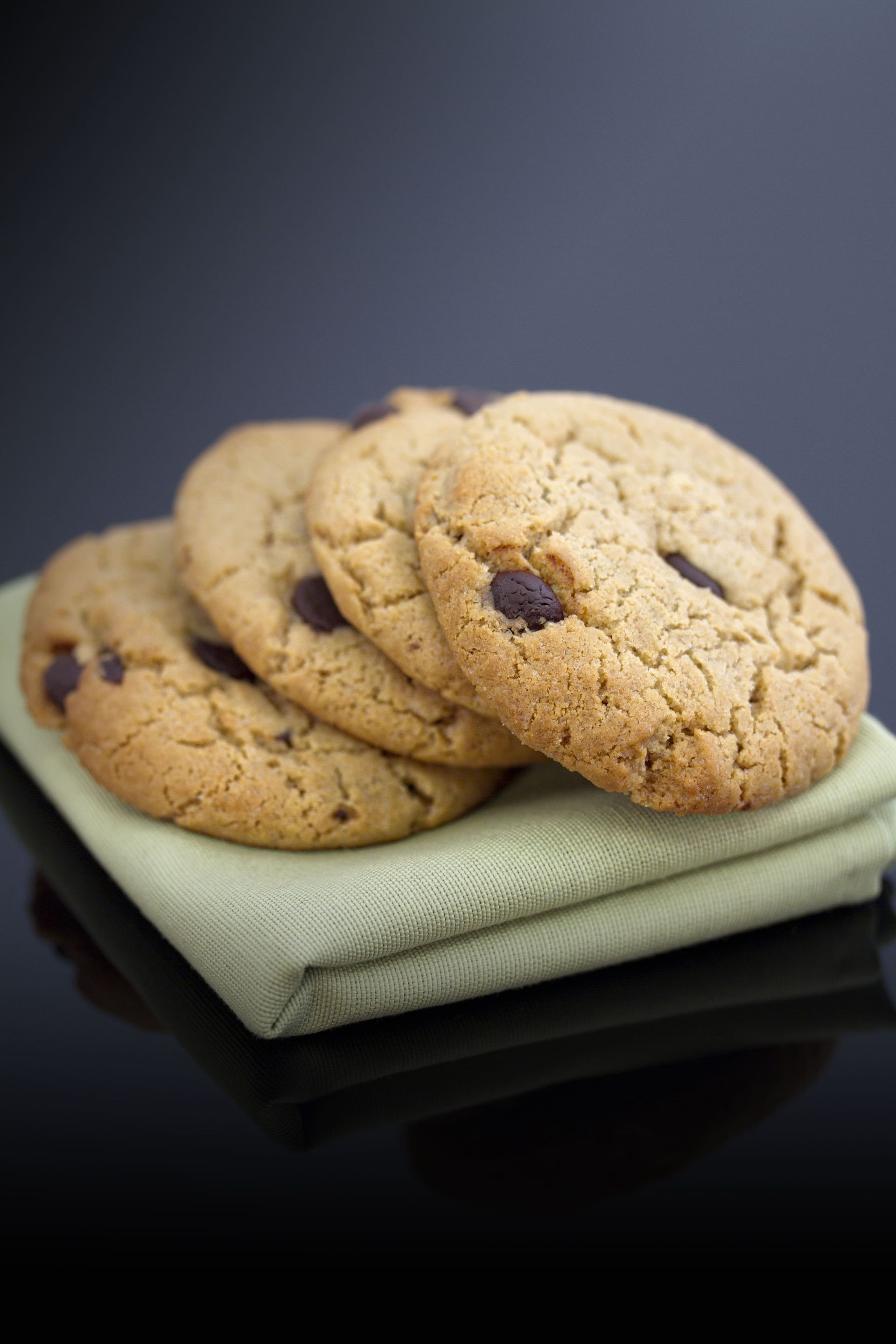 Quatre biscuits aux pépites de chocolat sont empilés les uns sur les autres sur une serviette.