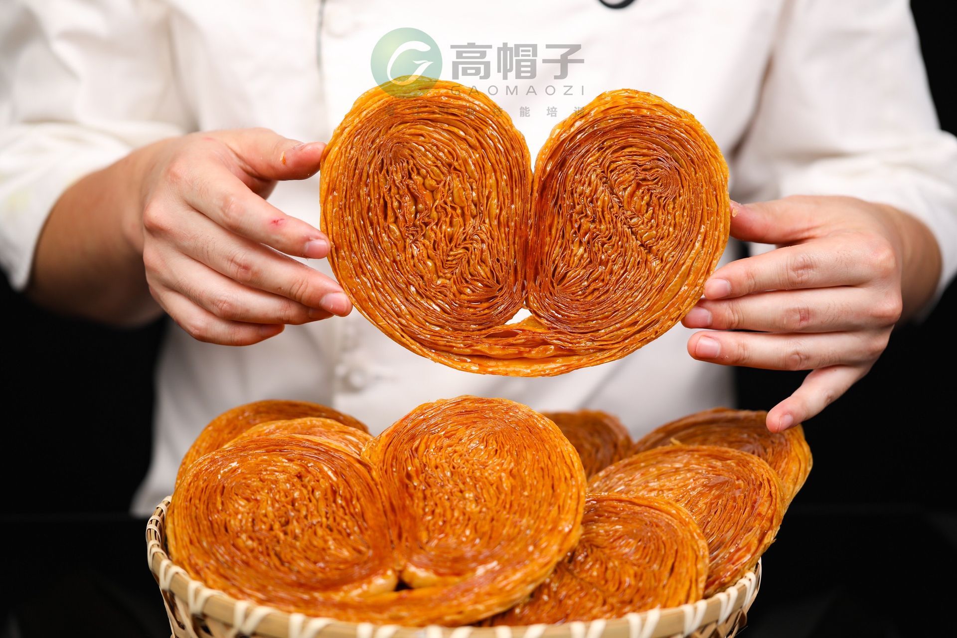 Une personne tient un biscuit en forme de cœur au-dessus d'un panier de biscuits.