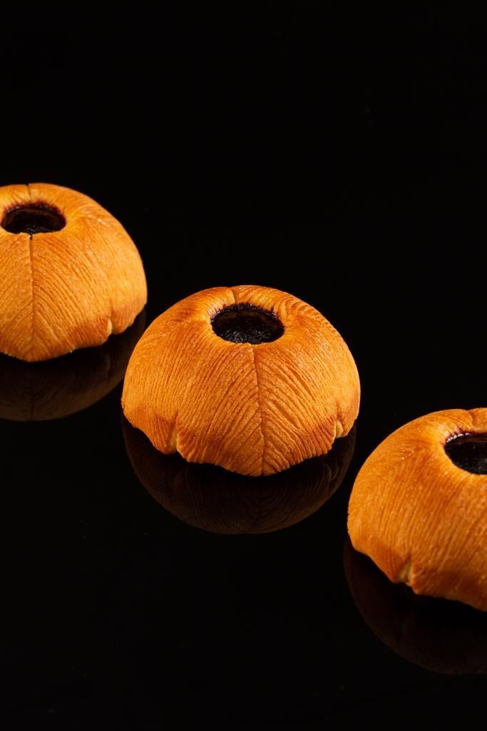 Trois boules de pain avec un trou au milieu sur une surface noire.