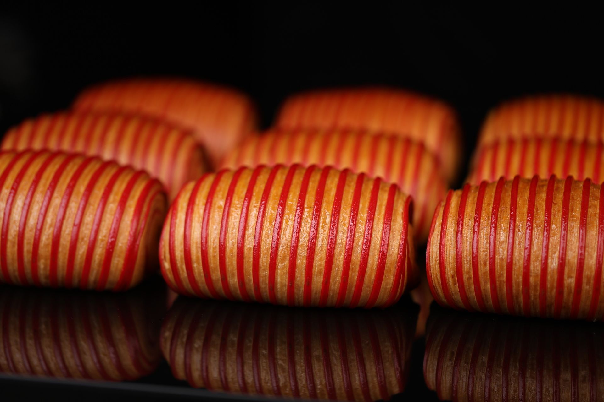 Une rangée de saucisses fumées enveloppées de bacon est posée sur une étagère.