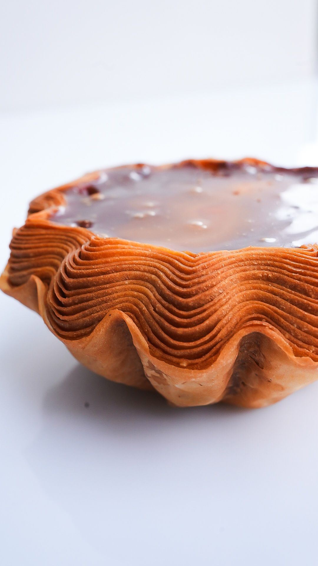 Un gros plan d'une tarte au chocolat sur une surface blanche.