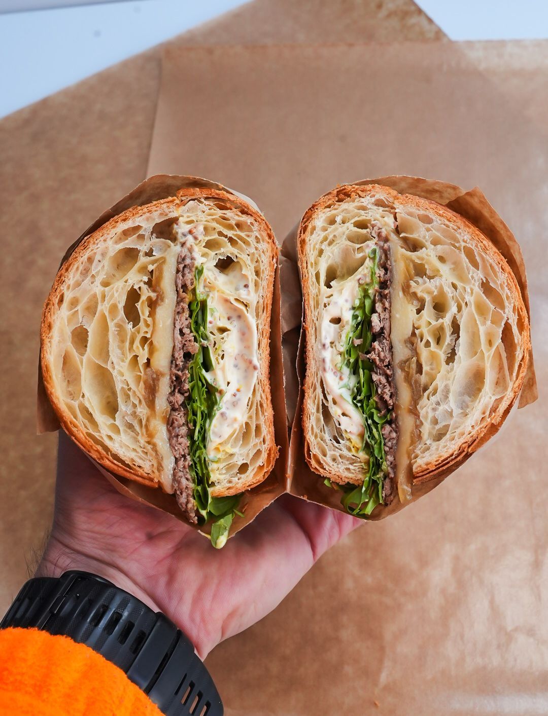 Une personne tient un sandwich à moitié mangé dans sa main.