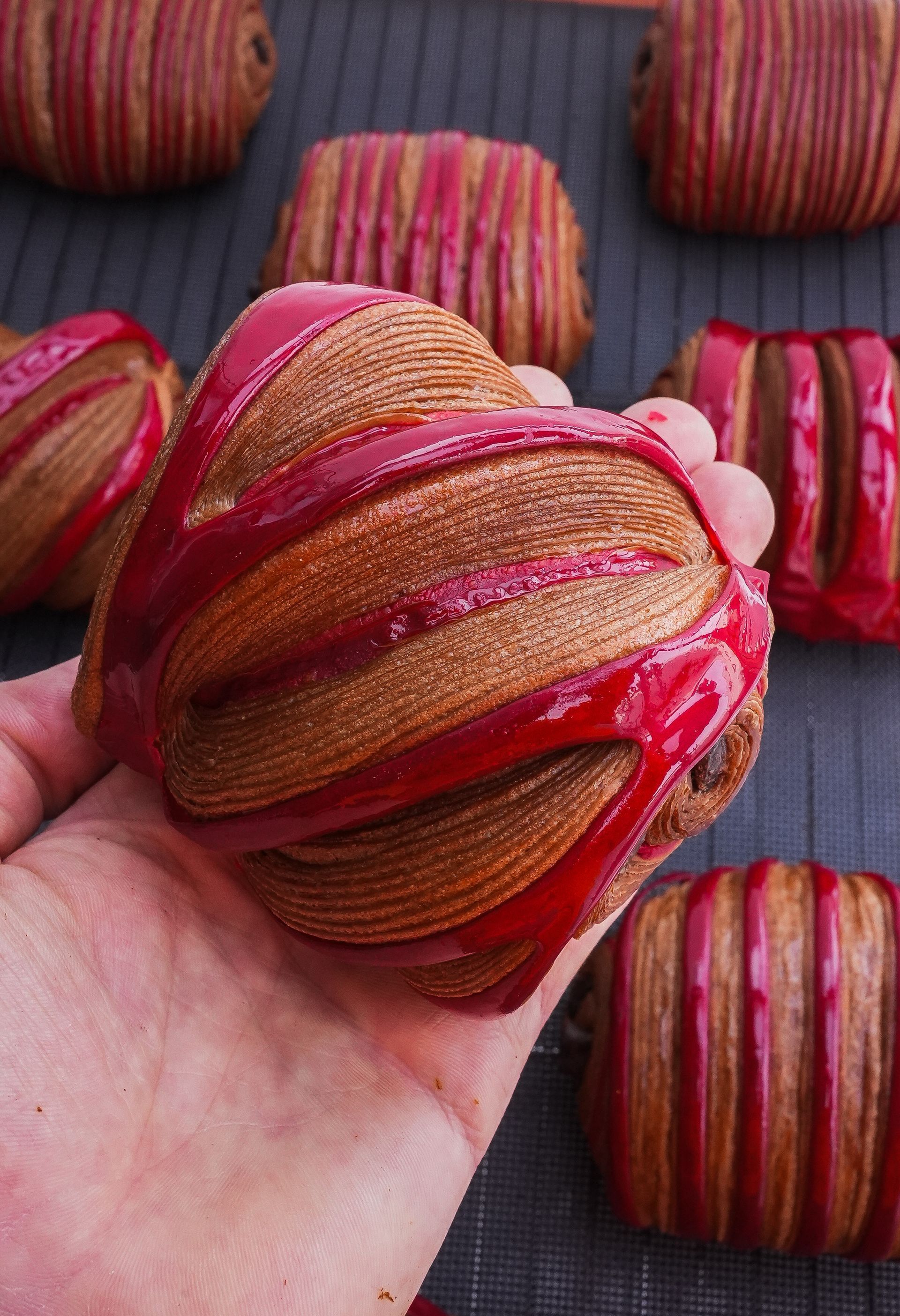 Une personne tient un biscuit avec du glaçage rouge dans sa main.