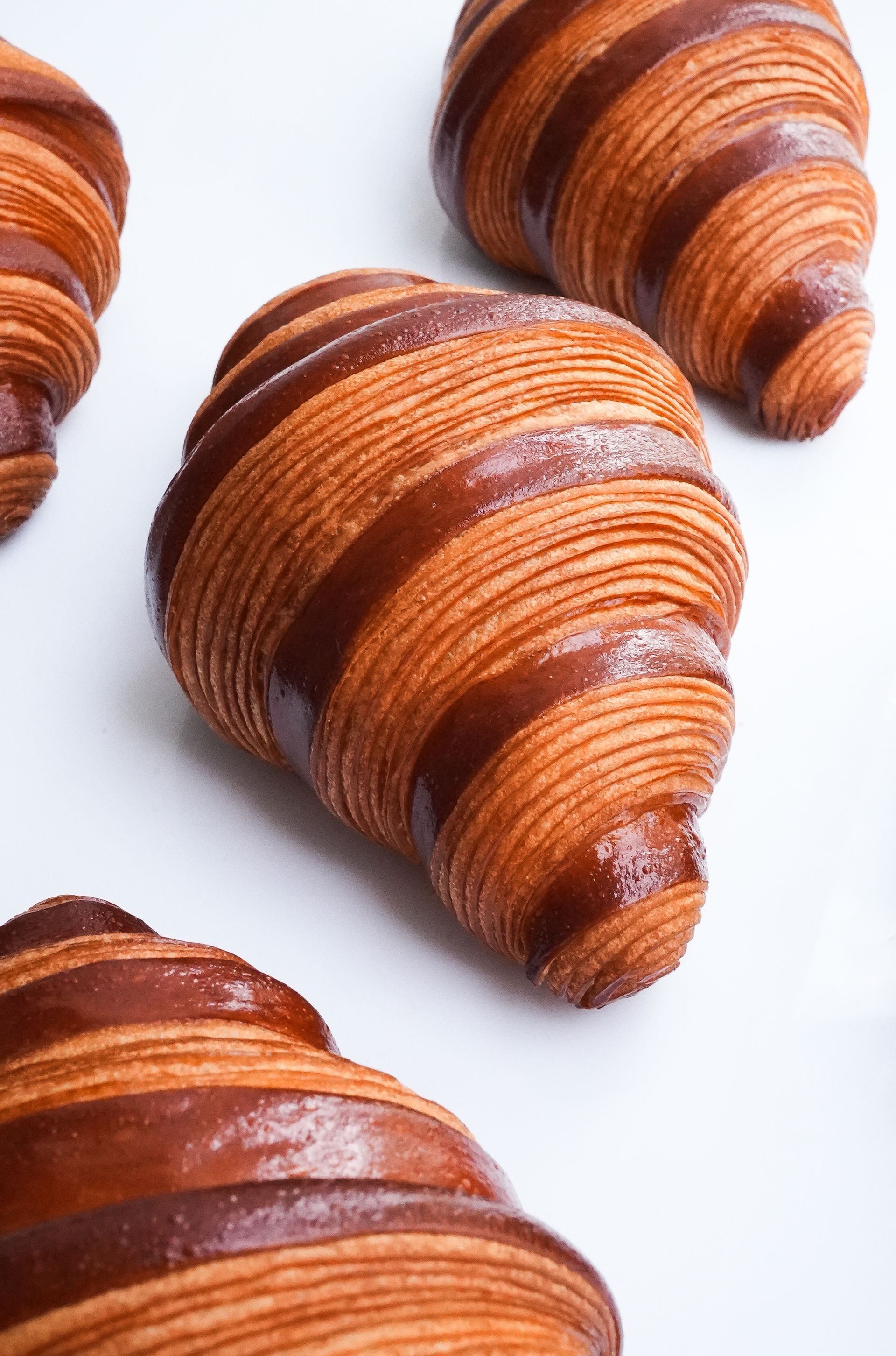 Un gros plan de trois croissants sur une surface blanche.