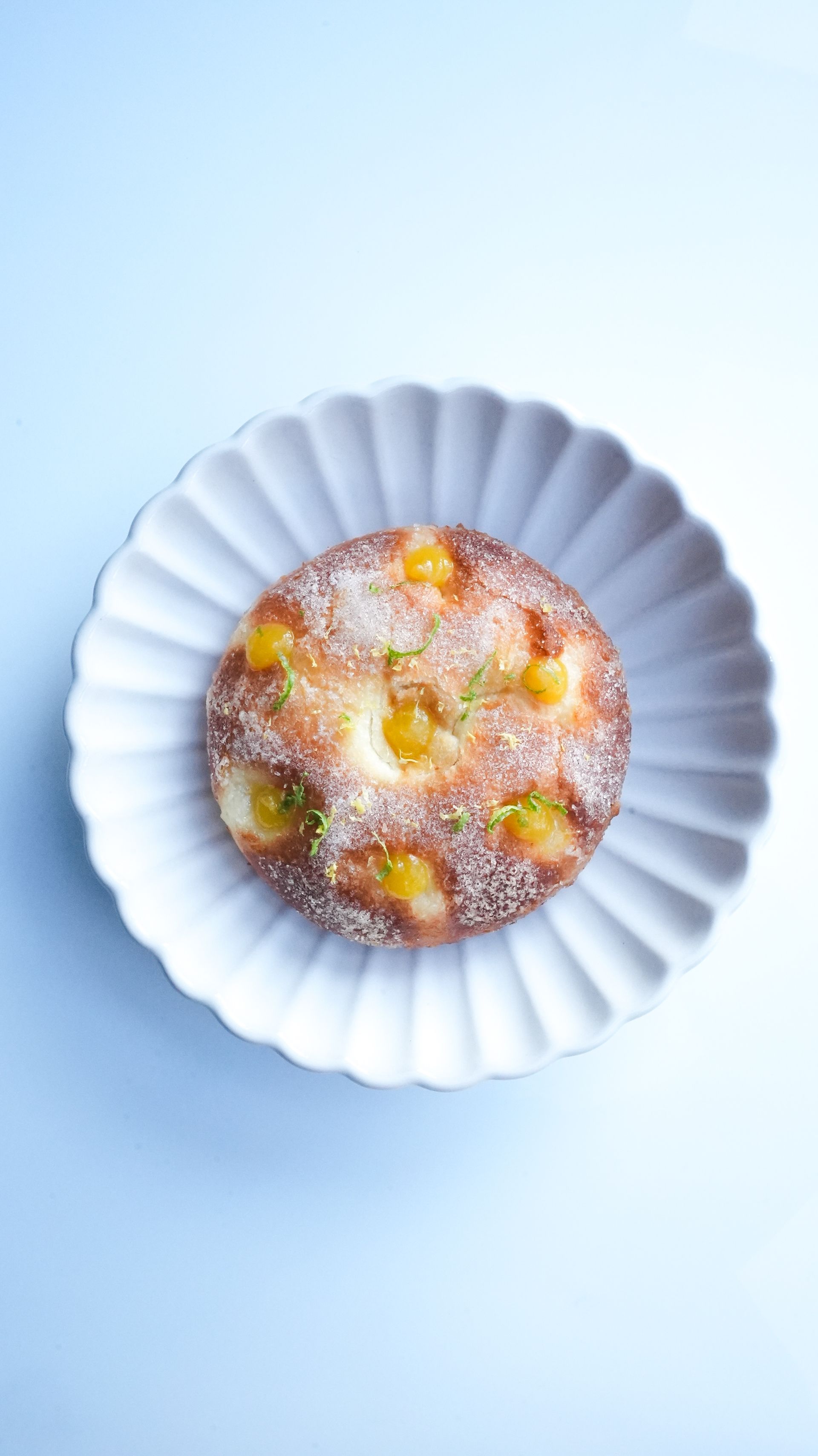 Une assiette blanche surmontée d'une pâtisserie sur une surface bleue.