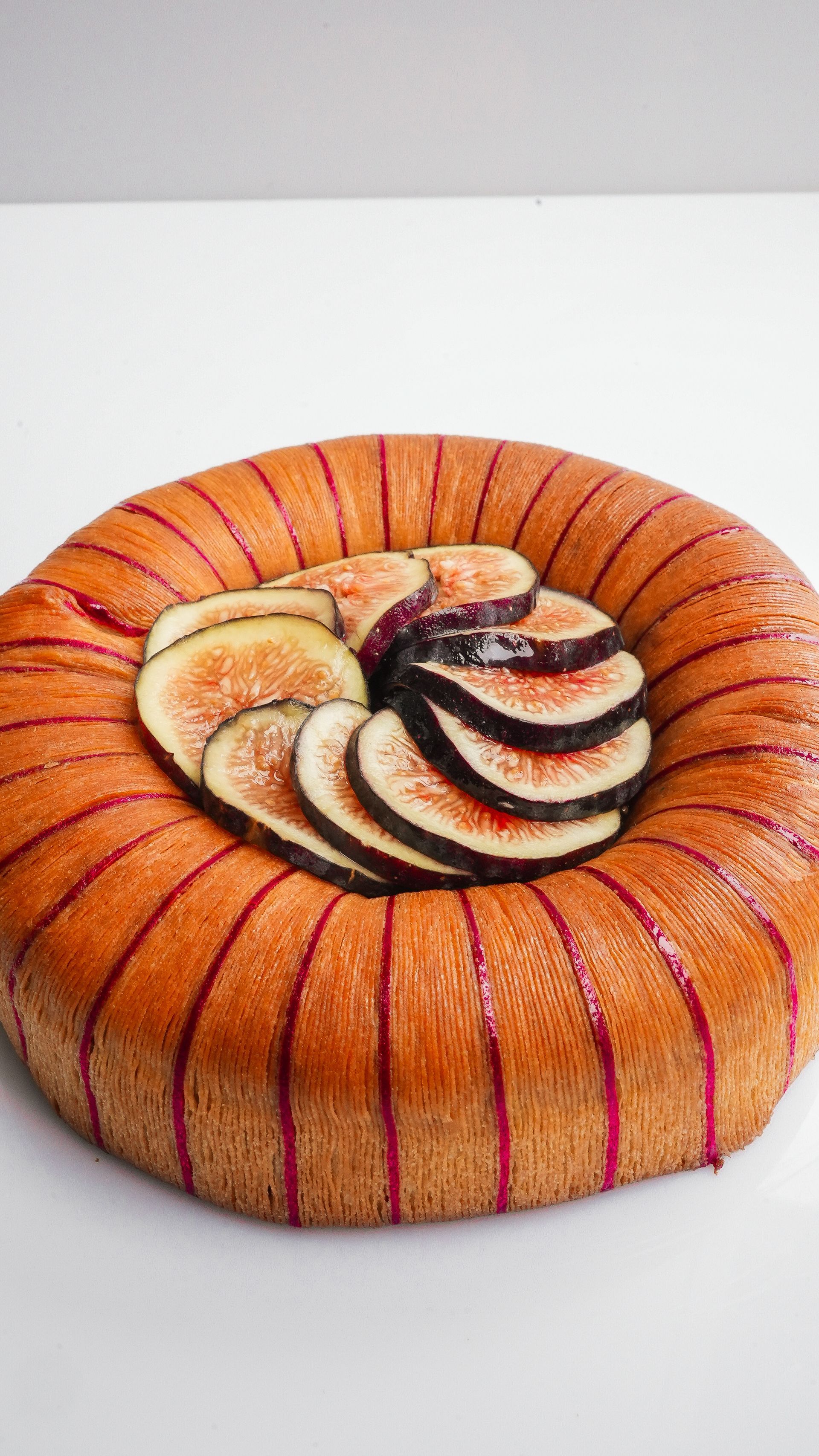 Un gâteau avec des figues coupées en tranches dessus sur une table blanche.