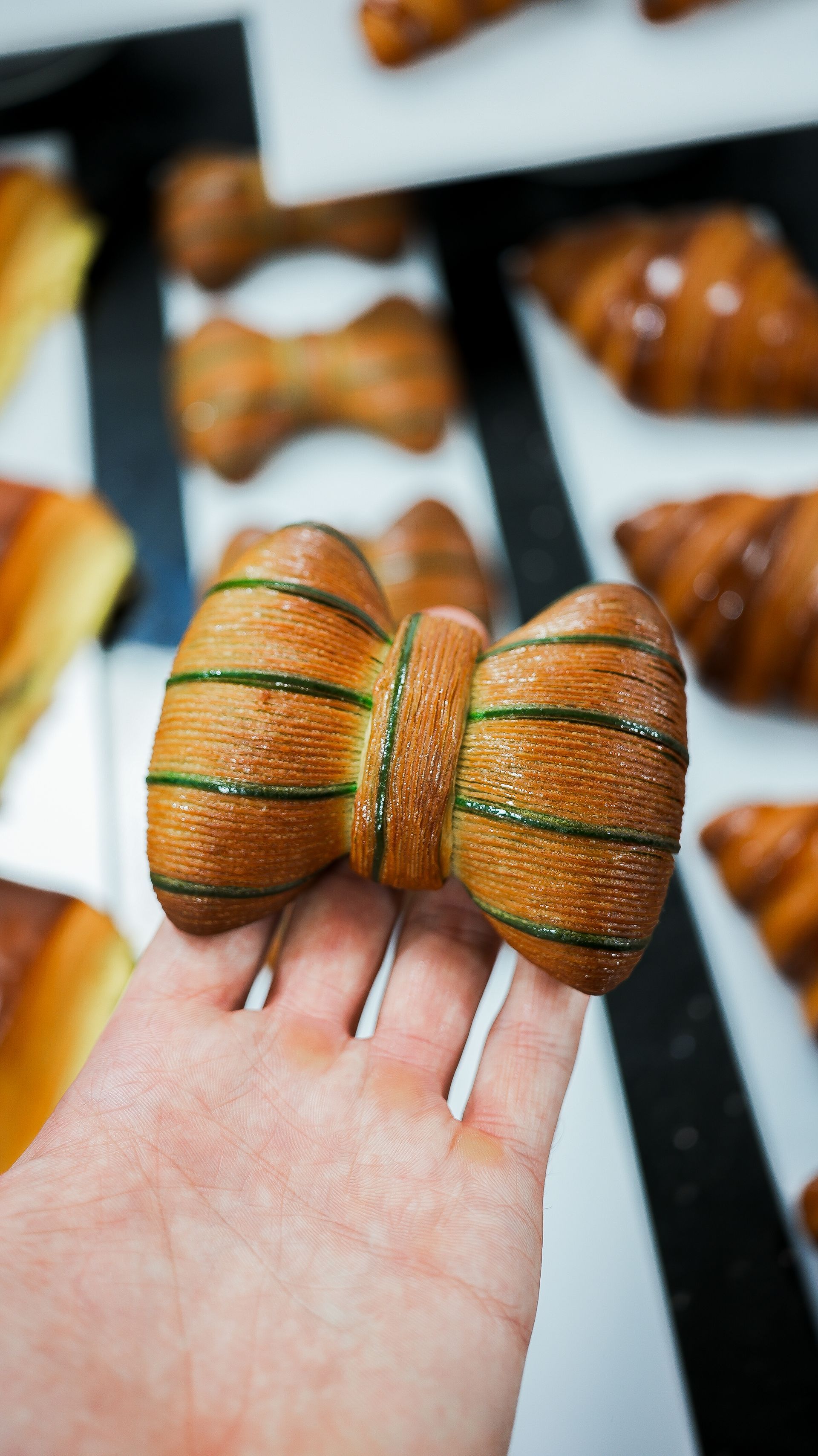 Une personne tient dans sa main une pâtisserie en forme de nœud papillon.