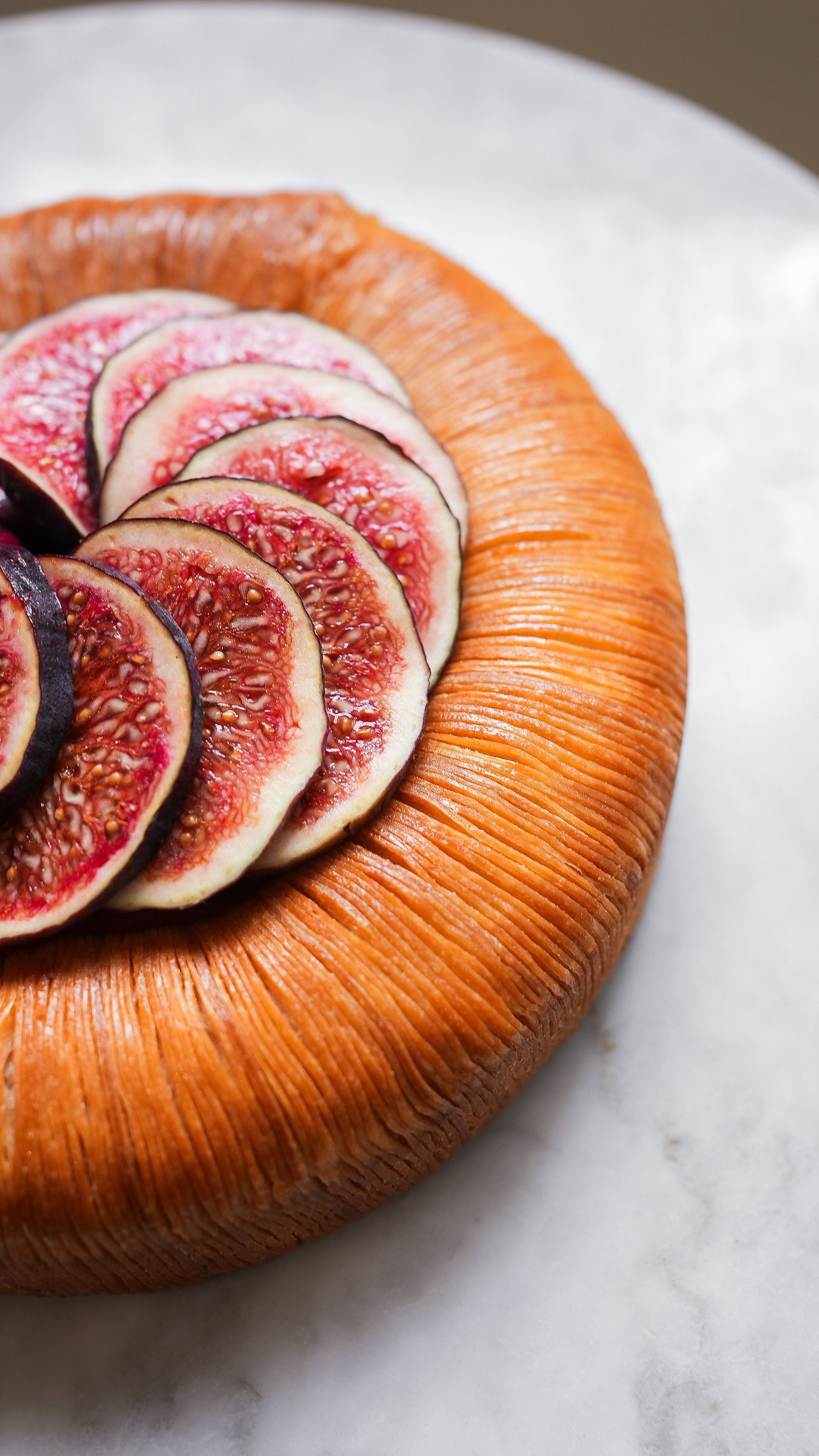 Une assiette en bois garnie de figues tranchées sur une table.