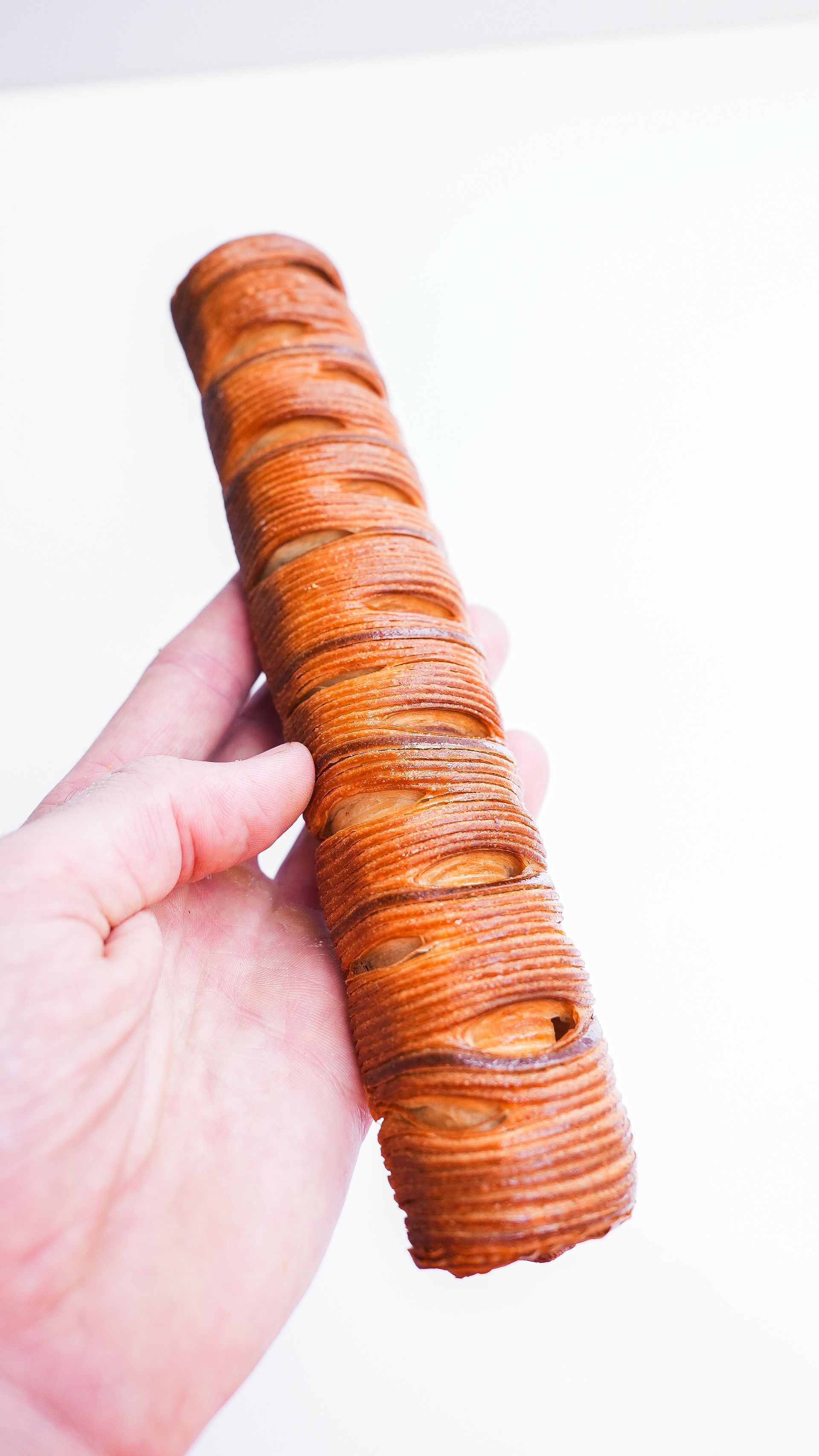 Une personne tient un long morceau de pain dans sa main.