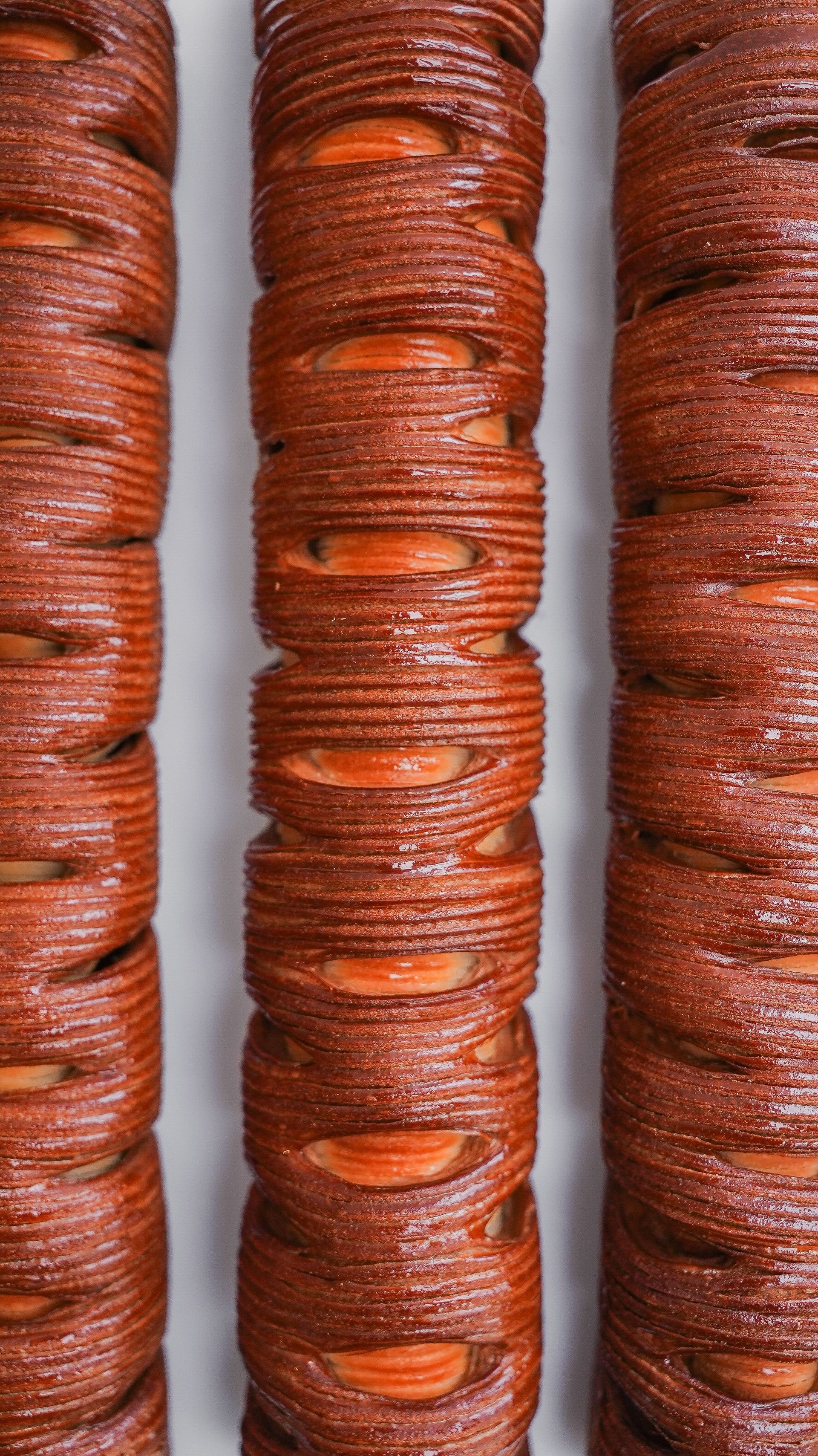 Un gros plan de trois rangées de bracelets marron sur une surface blanche.
