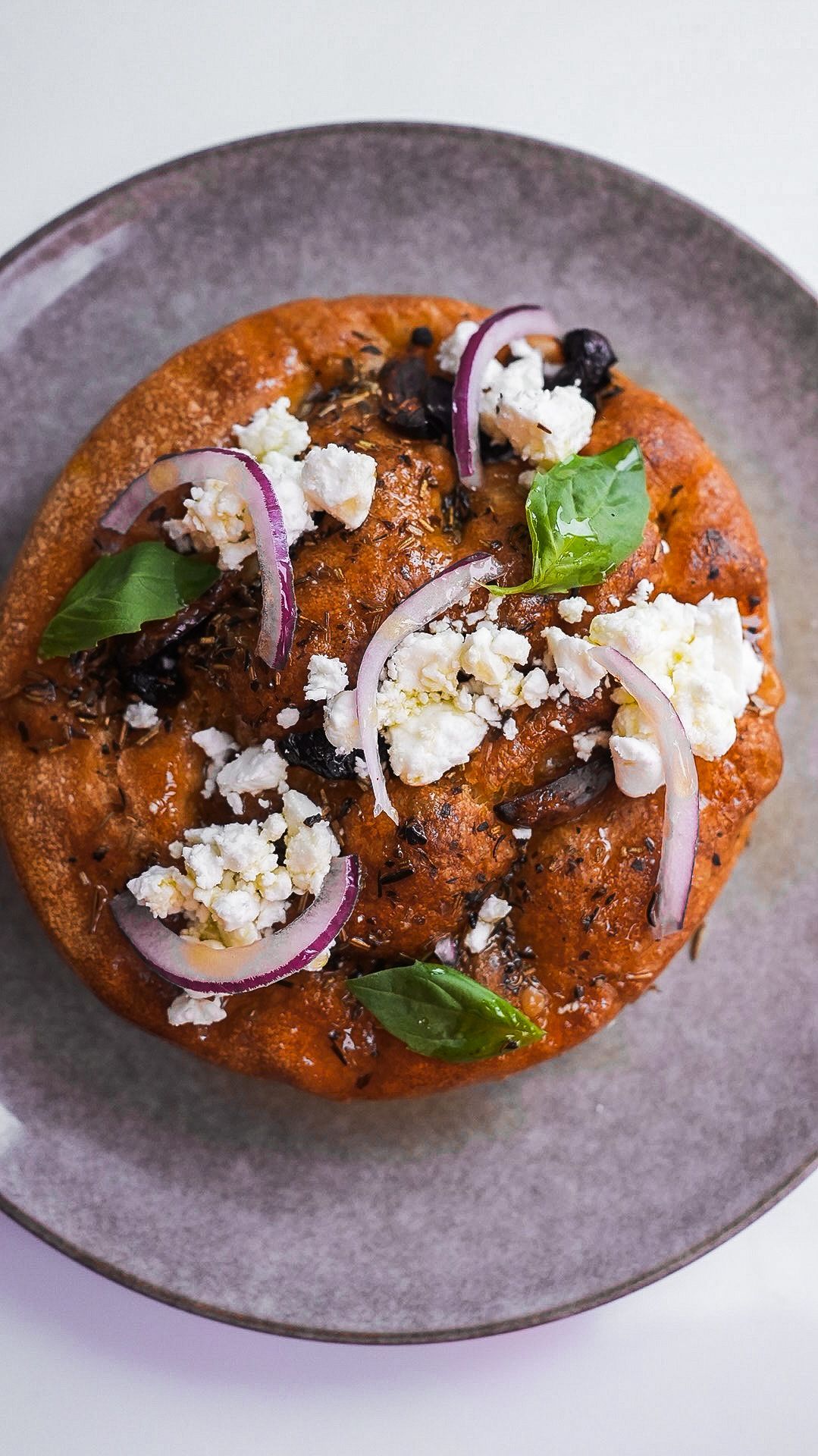 Une pizza avec des oignons et du fromage feta dans une assiette.