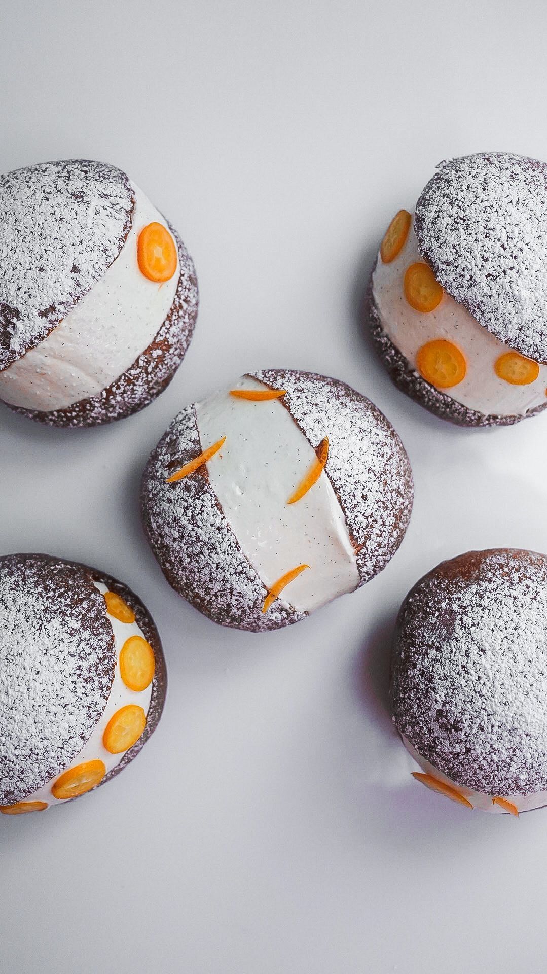 Un tas de beignets recouverts de sucre glace sont posés sur une table.