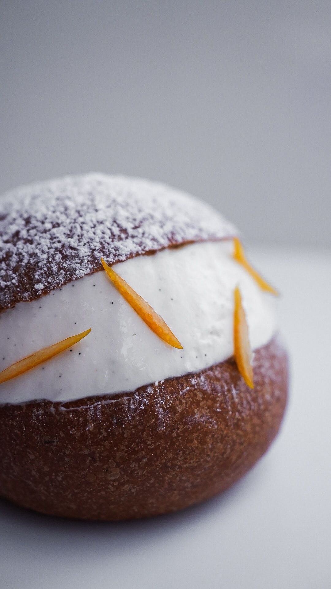 Un gros plan d'un beignet avec de la crème fouettée et du zeste d'orange sur une table.