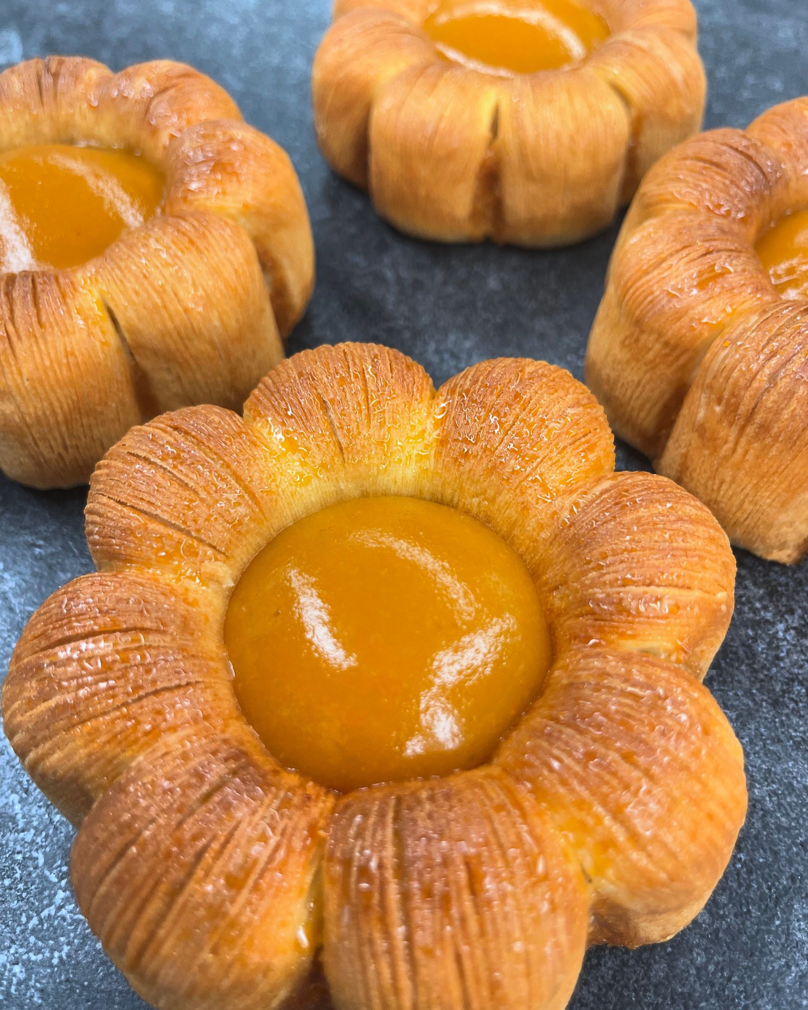 Un gros plan d'une pâtisserie en forme de fleur avec un centre jaune sur une table.