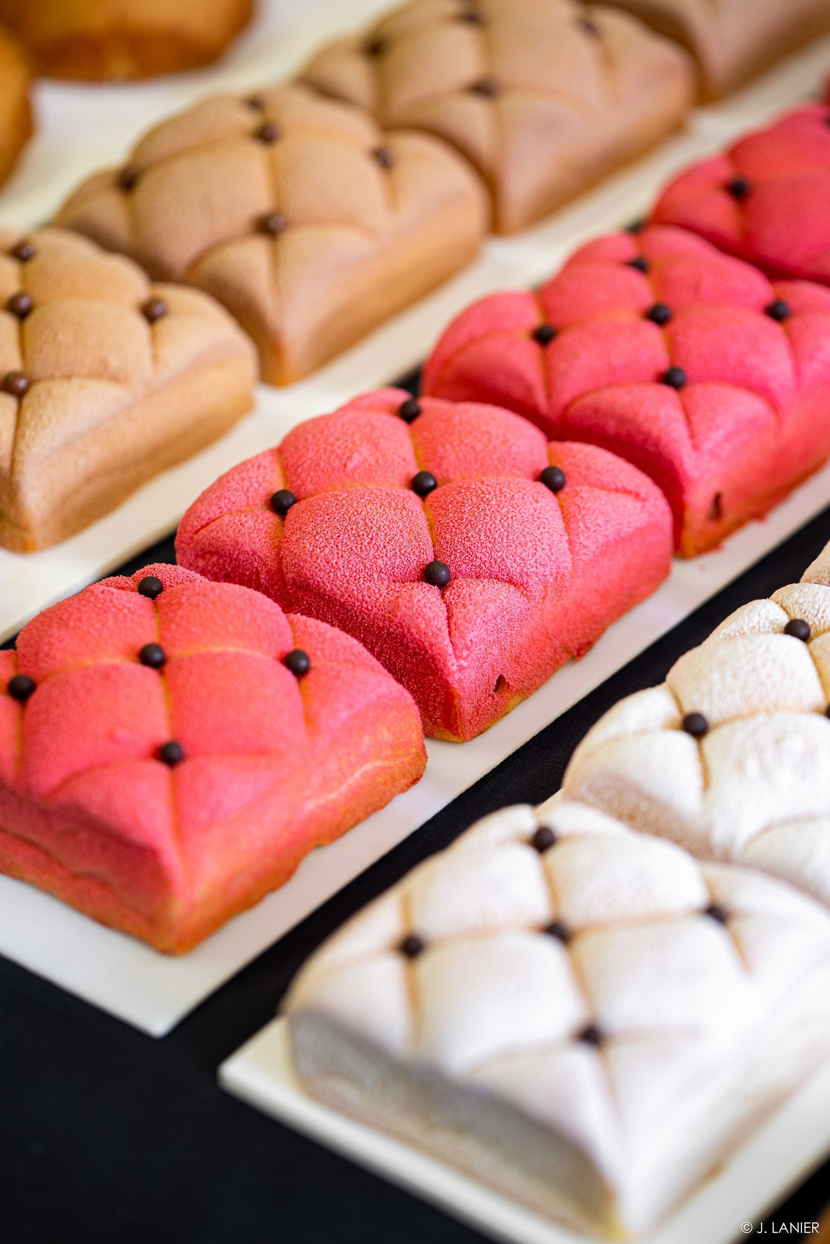 Un tas de gâteaux de différentes couleurs sont posés sur une table.