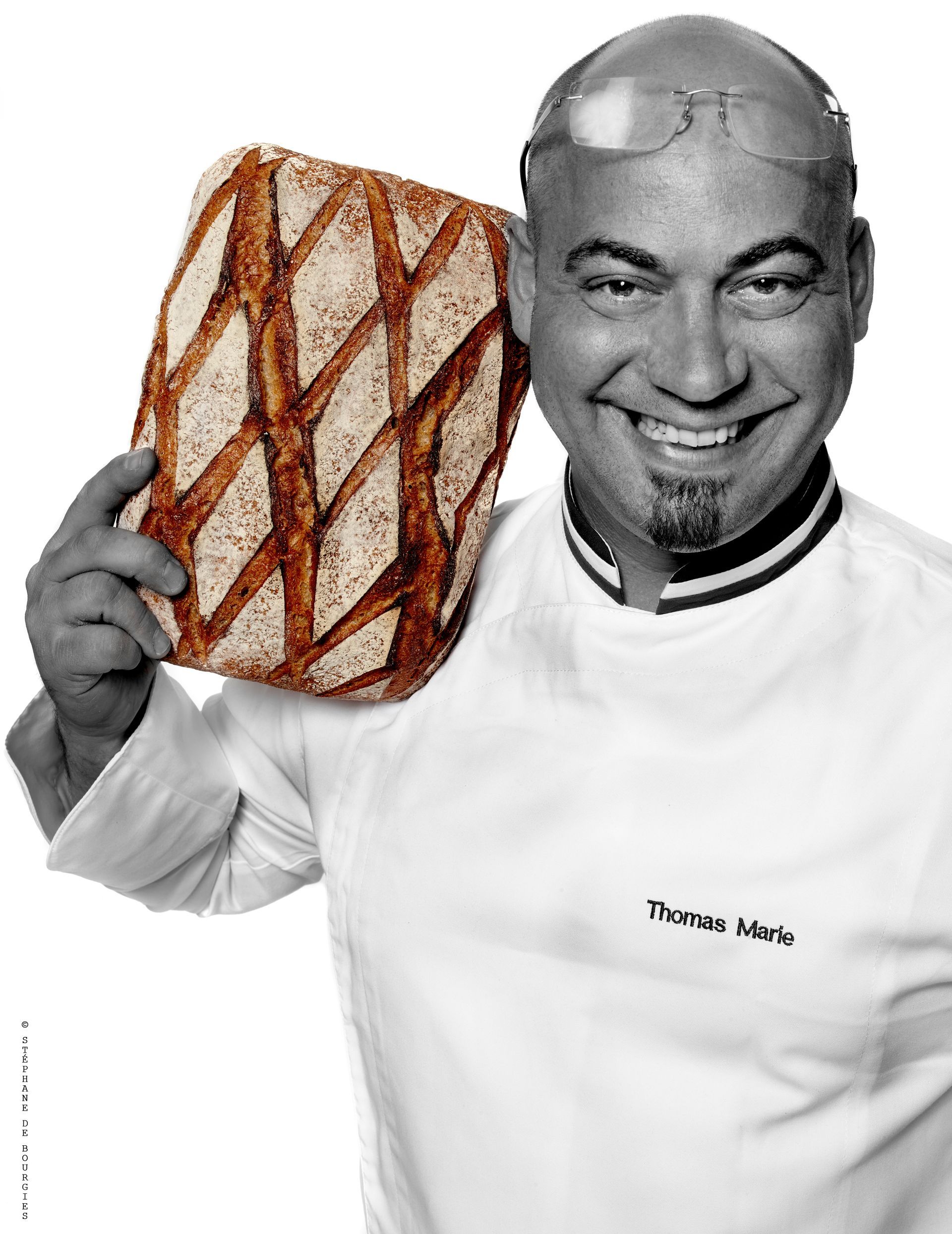 Un homme tient une miche de pain et sourit