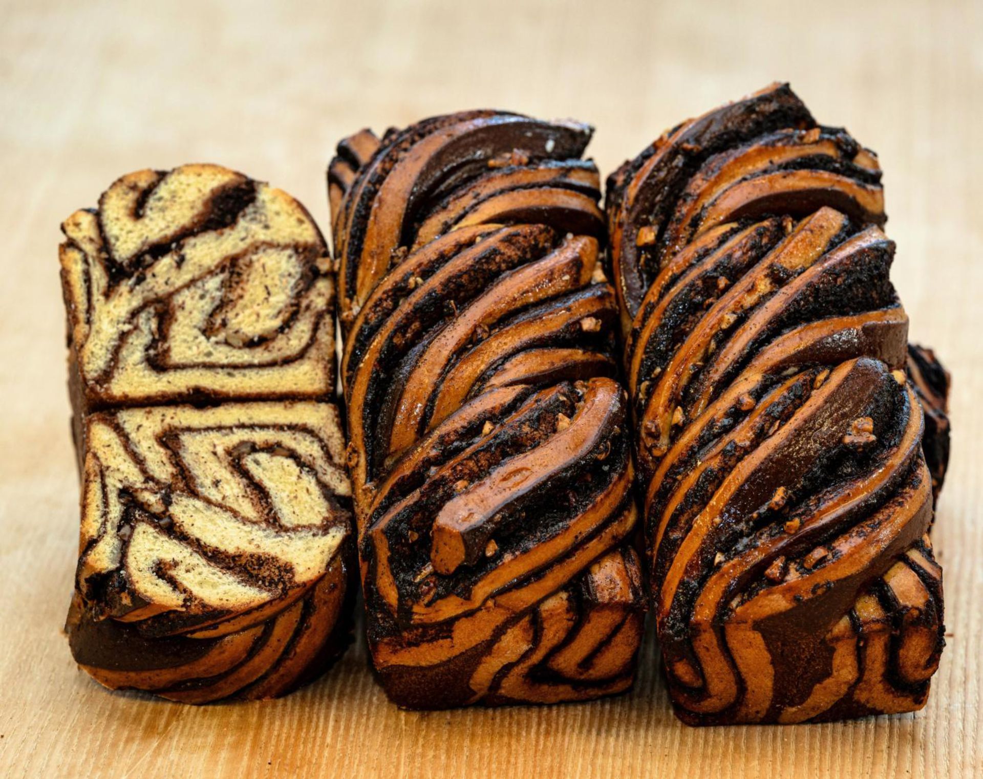 Trois morceaux de pain au chocolat sont empilés les uns sur les autres sur une table en bois.