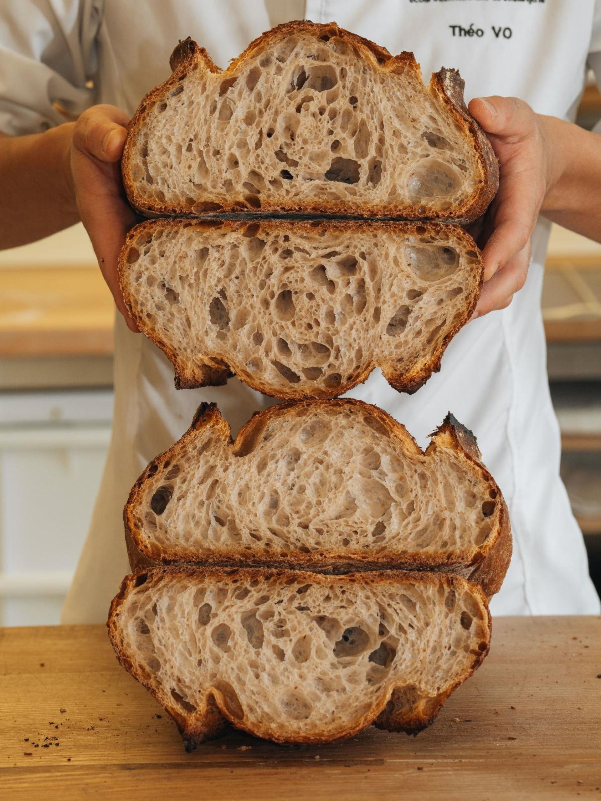 Une personne tient trois tranches de pain empilées les unes sur les autres.