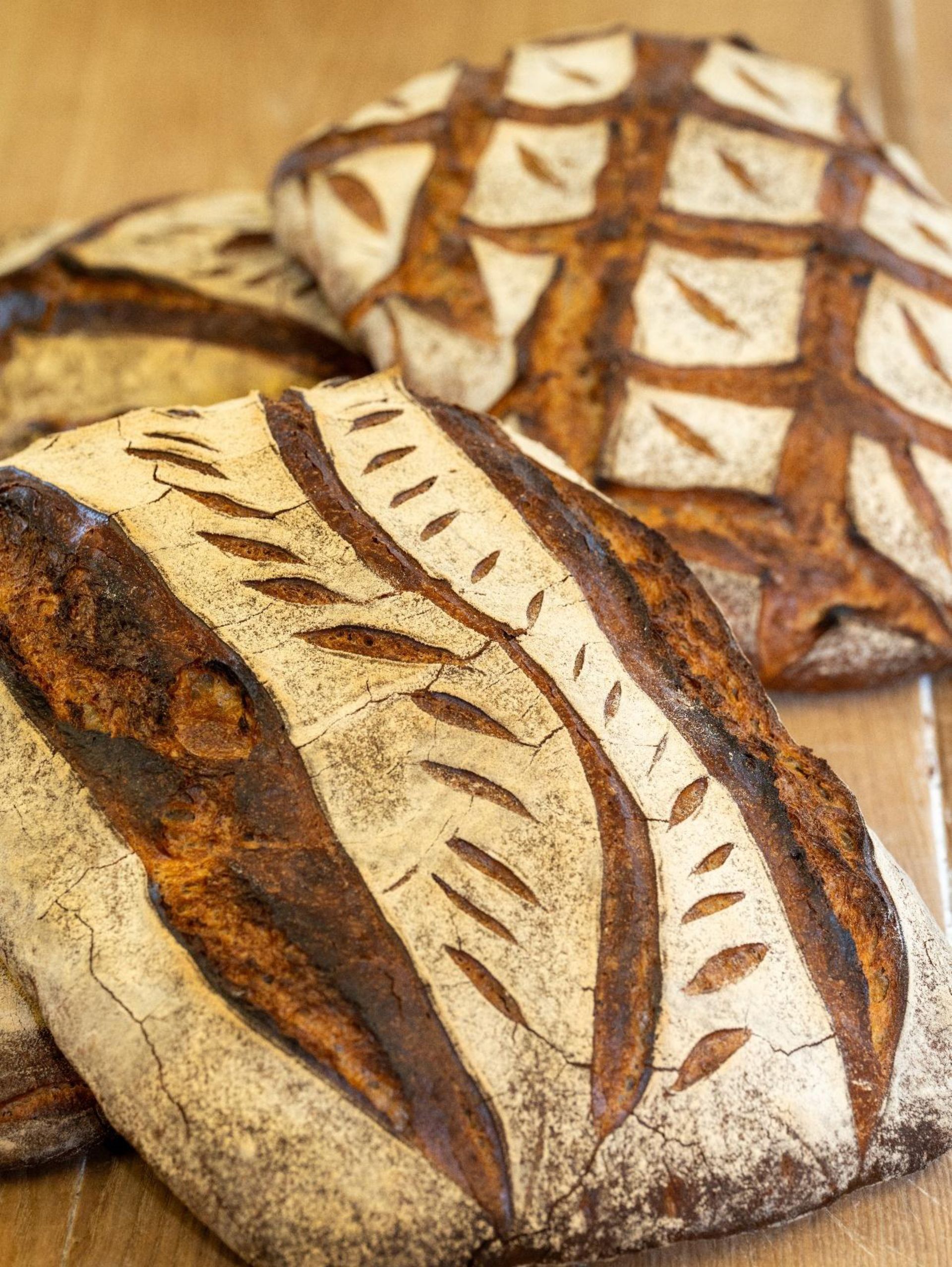 Trois pains sont posés les uns sur les autres sur une table en bois.