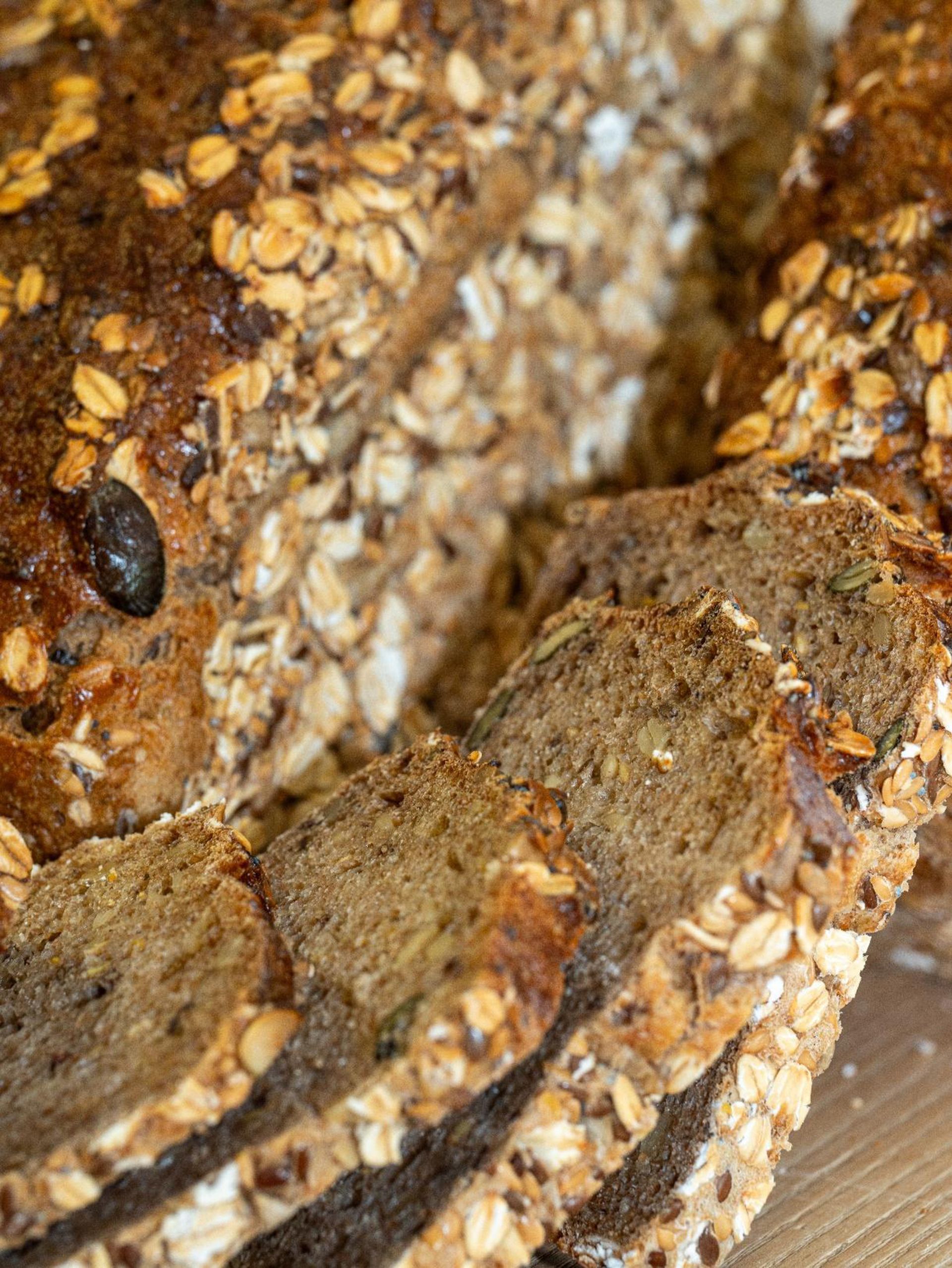 Un gros plan d'une miche de pain avec de l'avoine et des graines sur une table en bois.