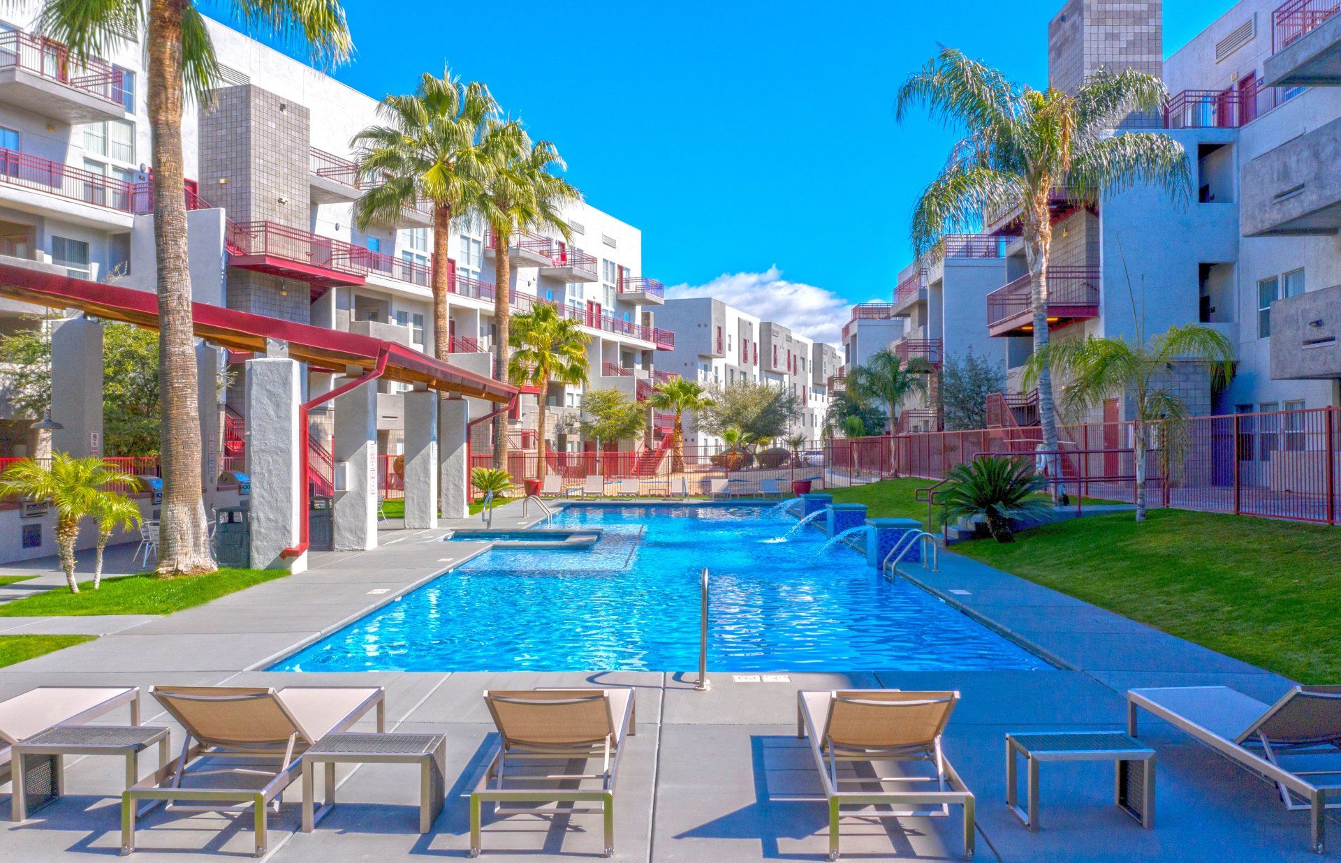 A sparkling pool with lounge chairs, a hot tub, and shaded BBQ area.