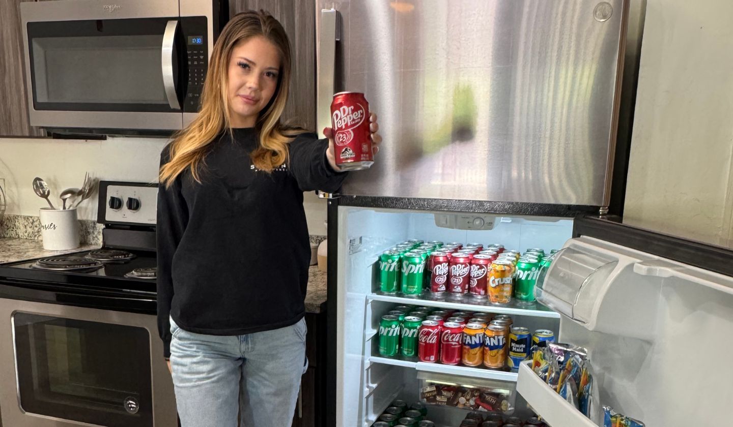 Resident showing the sodas in their stainless steel refrigerator.