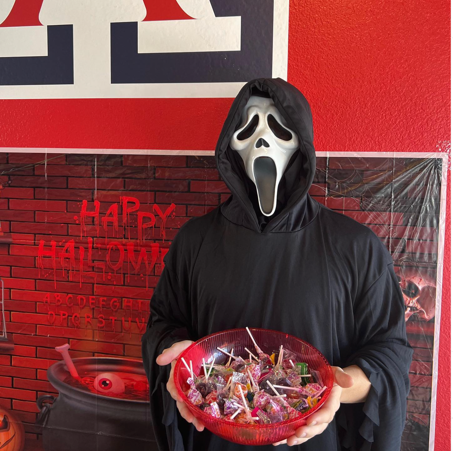 A resident dressed in a Scream costume holding a bowl of candy.